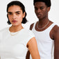 Woman models ELIYAH necklace, silver-plated with textured, nature-inspired links, while man in background wears a similar chain, showcasing minimalist elegance.