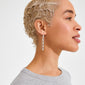 ELIYAH chain earrings silver-plated, featuring sculptural, droplet-shaped charms, hang elegantly, complementing the model's bleached finger-wave hair against a plain white background.