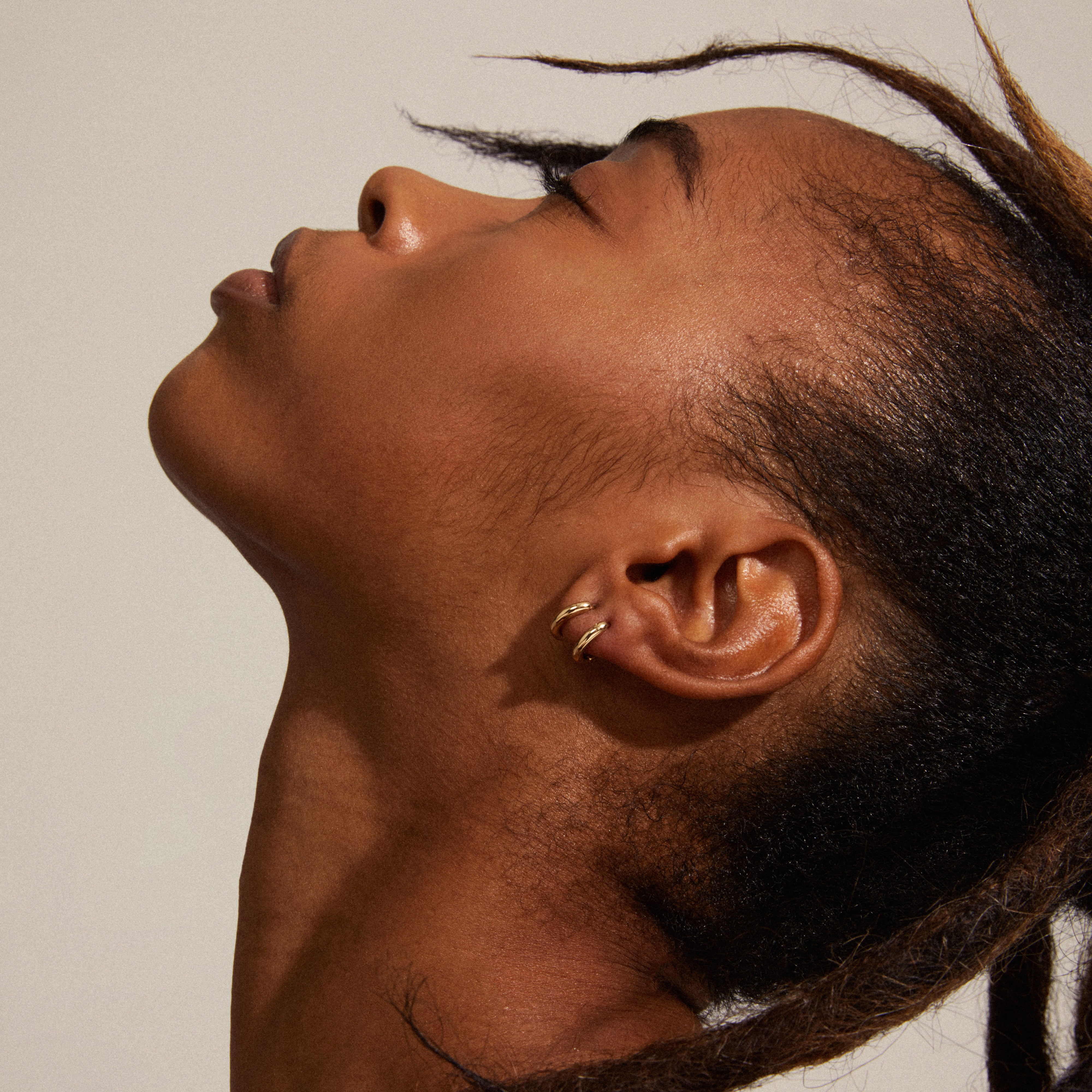 TYRA chunky mini hoop earrings gold-plated, featured in a close-up portrait, showcasing their sleek, minimalist design and highlighting Pilgrim's sustainable craftsmanship.
