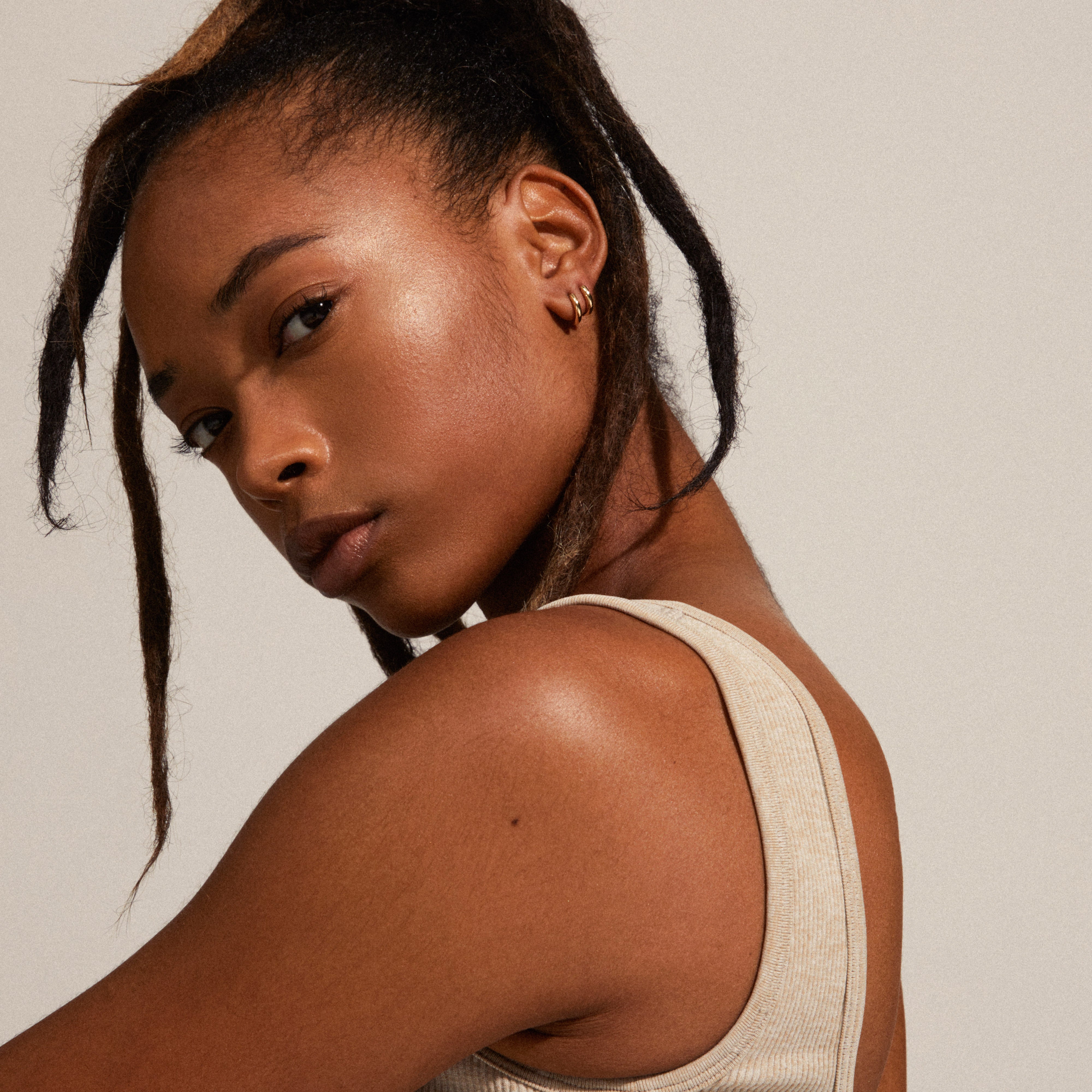 TYRA chunky mini hoop earrings gold-plated, worn by a woman with long hair, showcasing their simple, classic design from Pilgrim's recycled collection.