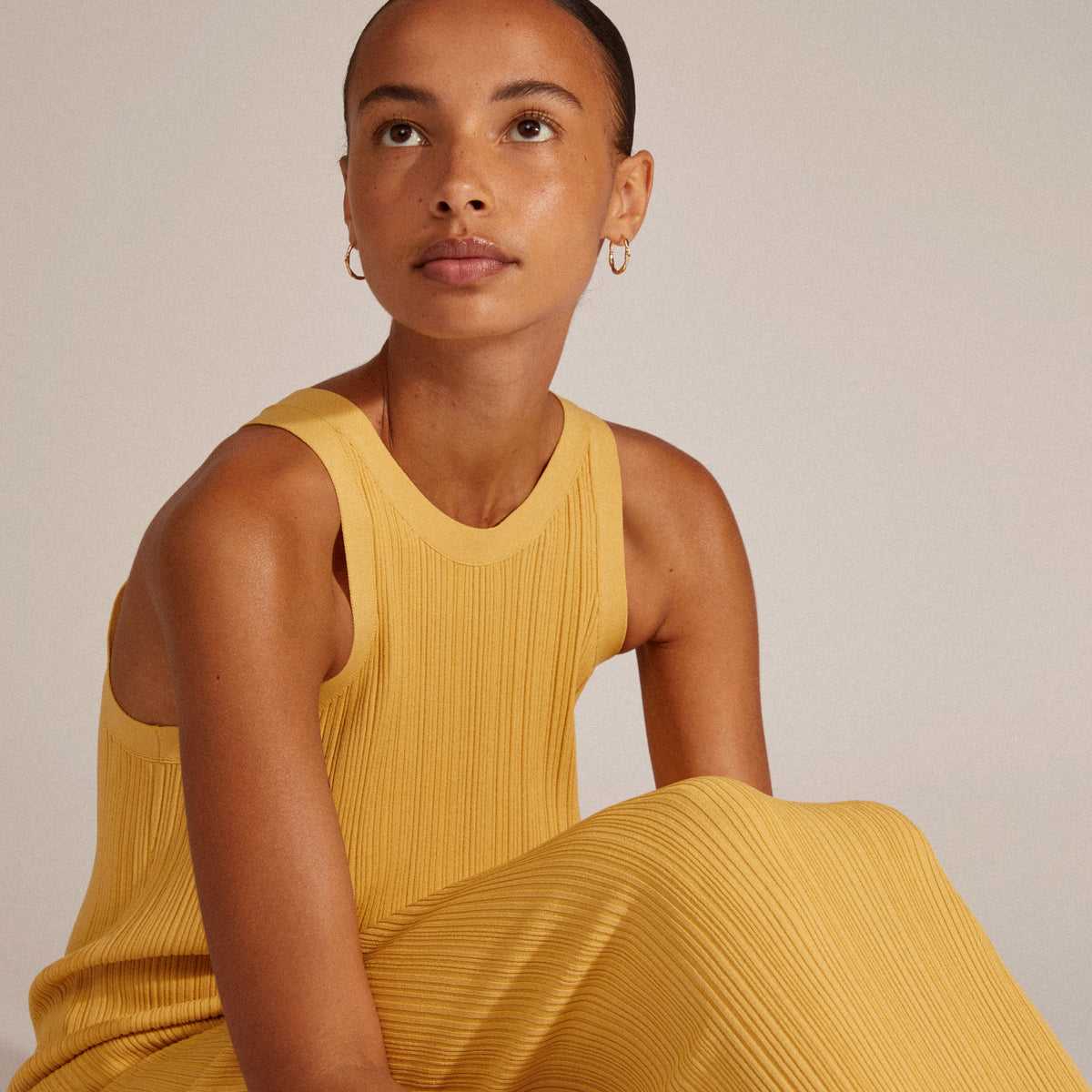 EDDY organic-shaped large hoops gold-plated worn by a woman in a yellow dress, showcasing their unique handcrafted design.