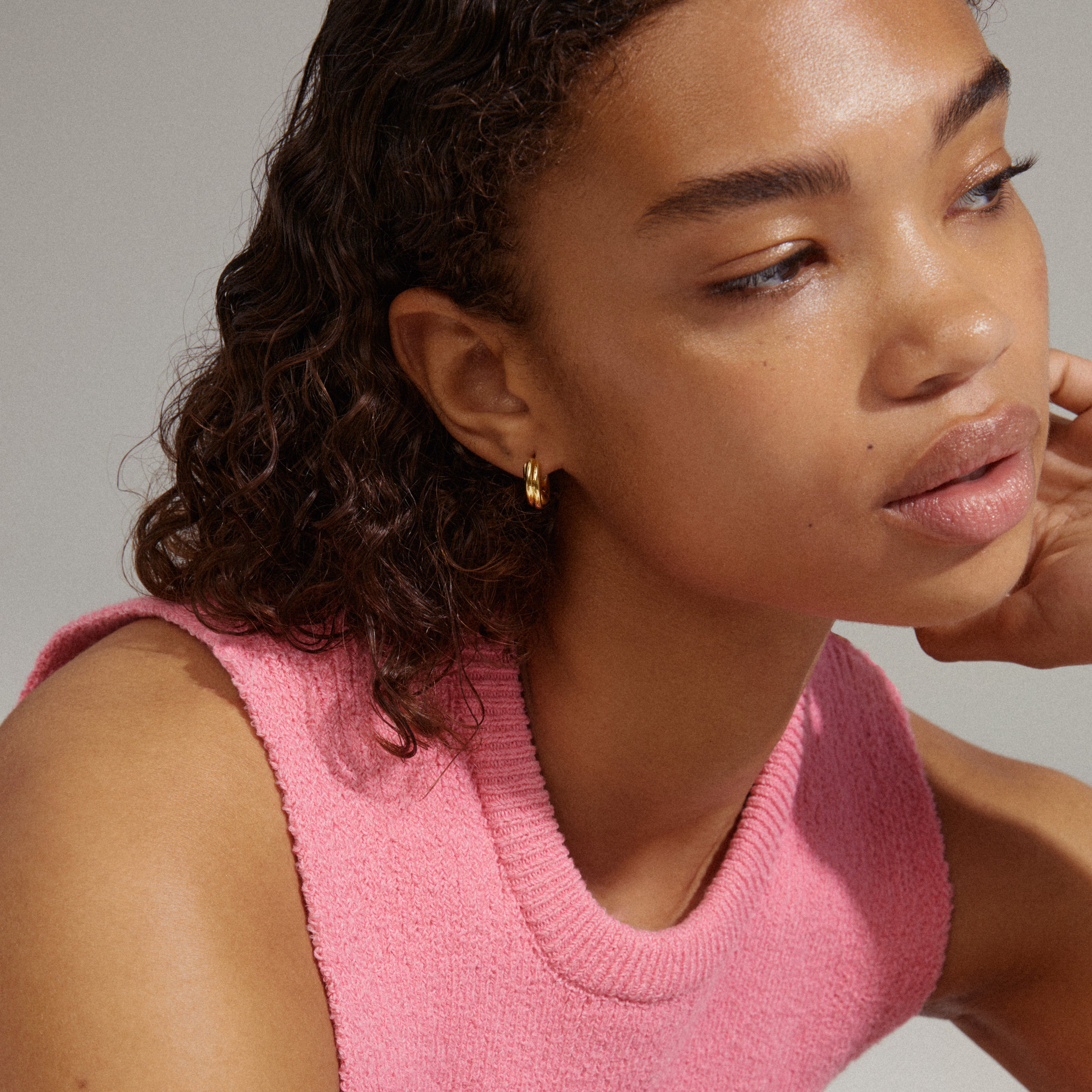 Woman wearing EDEA chunky huggie hoops gold-plated earrings, showcasing their elegant, wide design against a close-up of her neck and ear.