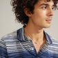 AFRODITTE heart necklace, silver-plated, worn by a man with curly hair in a blue and white striped shirt, featuring a heart pendant.