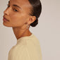 Close-up of a woman wearing EDDY organic shaped maxi hoops, silver-plated earrings, showcasing their elegant, wavy design.