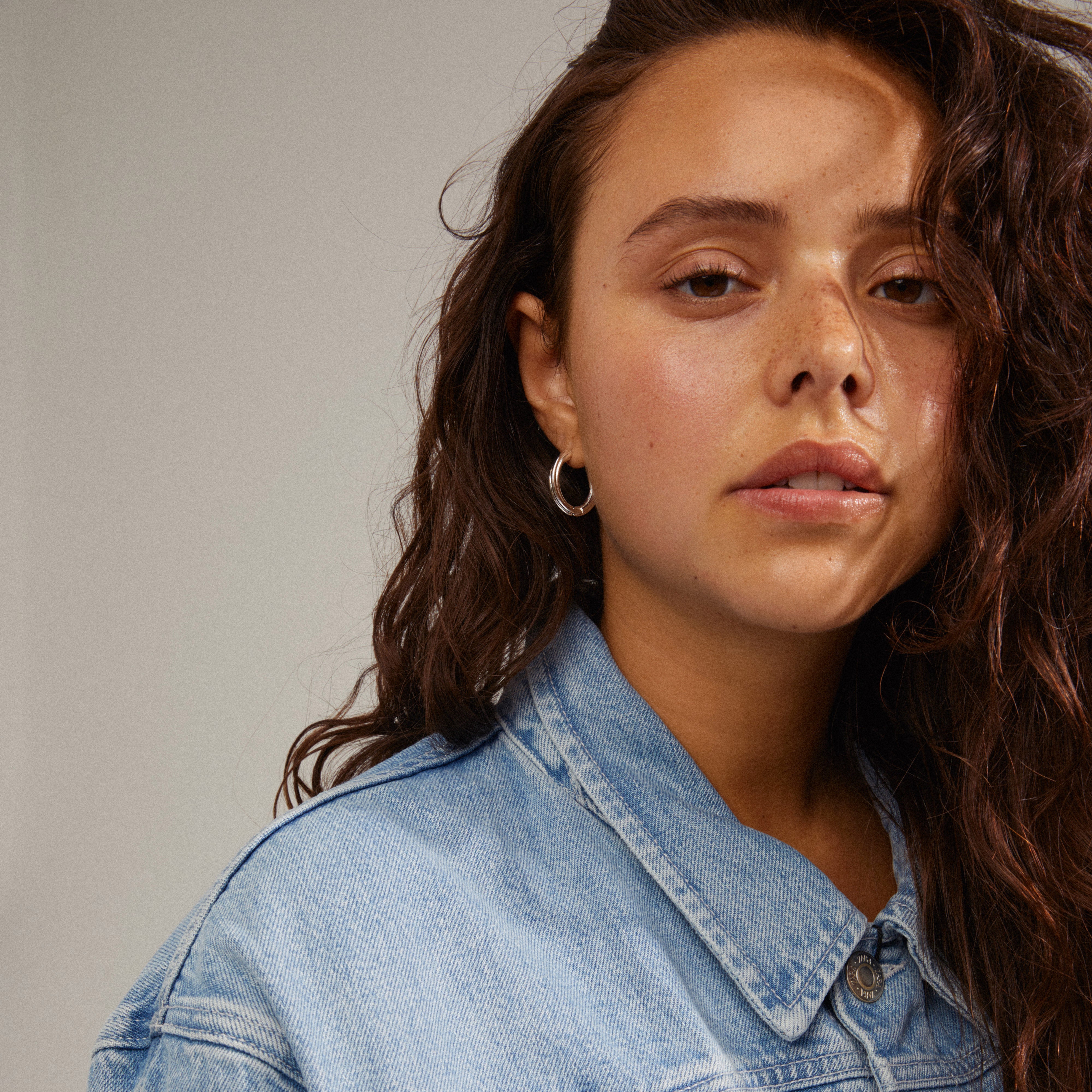 EDEA hoops silver-plated earrings worn by a woman, showcasing their elegant, chunky design and slightly twisting structure, highlighting their versatile style.