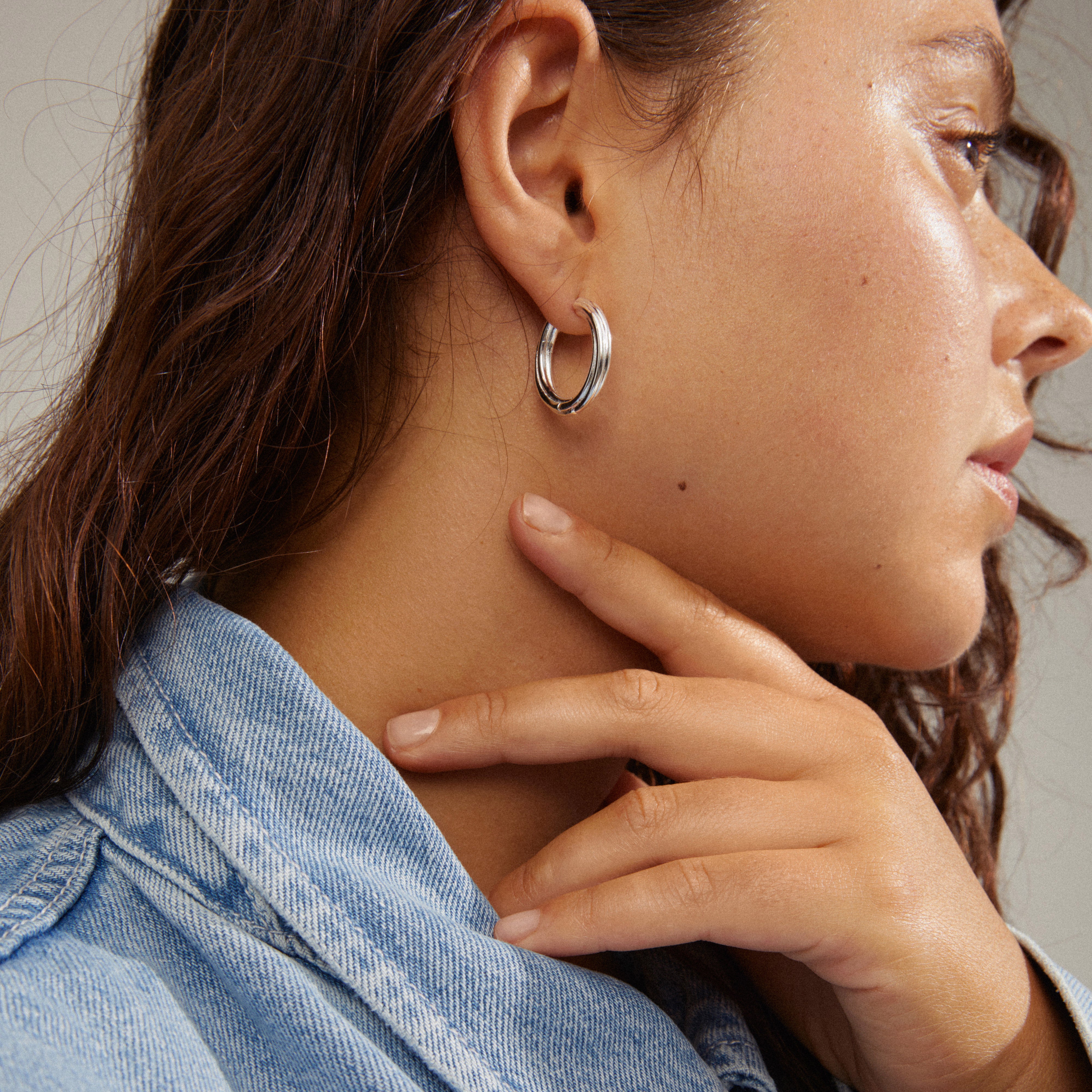 Close-up of a woman wearing silver-plated EDEA hoops, featuring a chunky, slightly twisted design with a secure click lock.