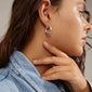Close-up of a woman wearing silver-plated EDEA hoops, featuring a chunky, slightly twisted design with a secure click lock.