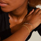 Woman wearing Pilgrim's REIGN bracelet, a gold-plated 2-in-1 set featuring a curb chain and Preciosa crystals, showcasing stylish urban elegance on her wrist.