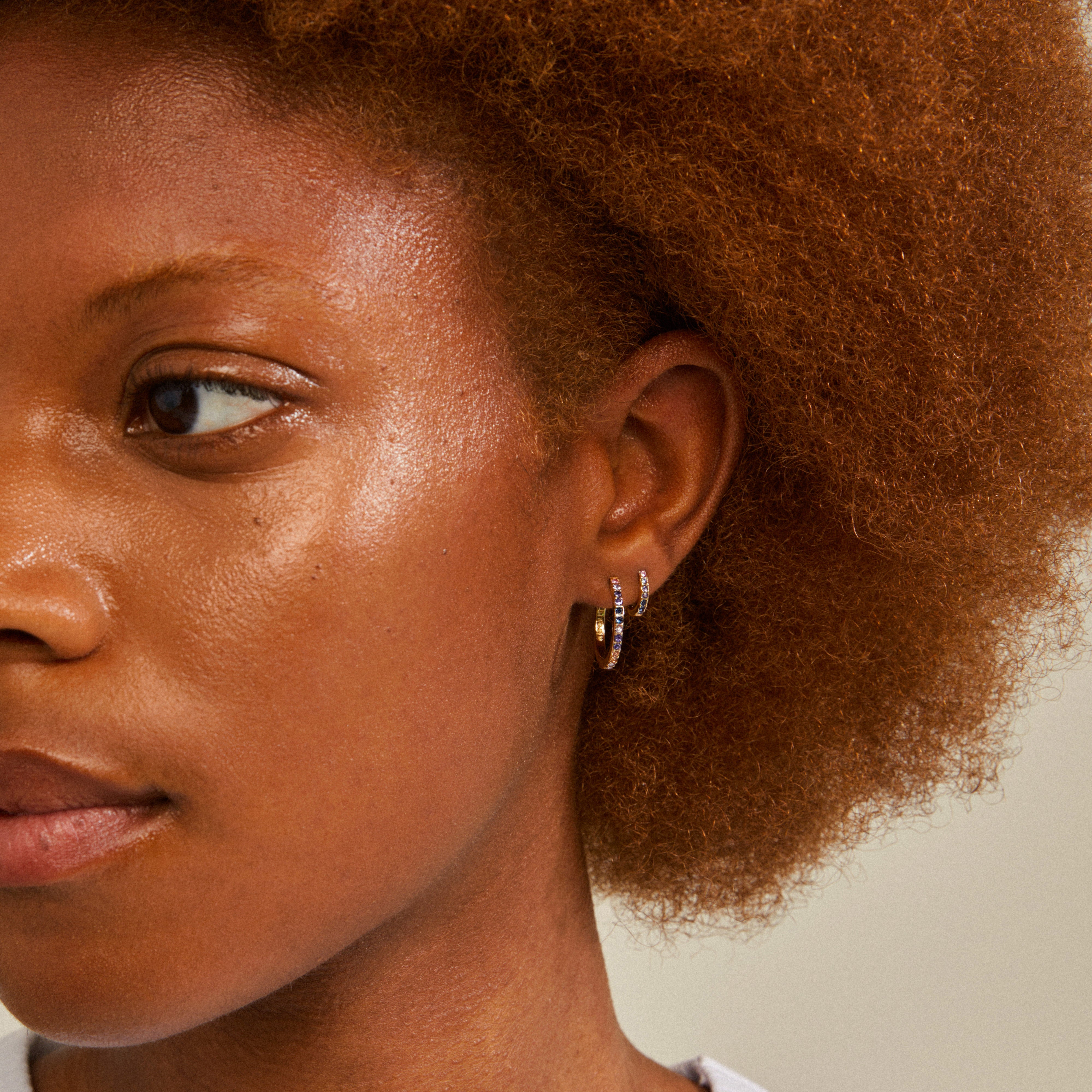 REIGN hoops, a gold-plated 2-in-one set, featuring small and medium hoops adorned with blue and champagne crystals, enhancing both basic and glam outfits.