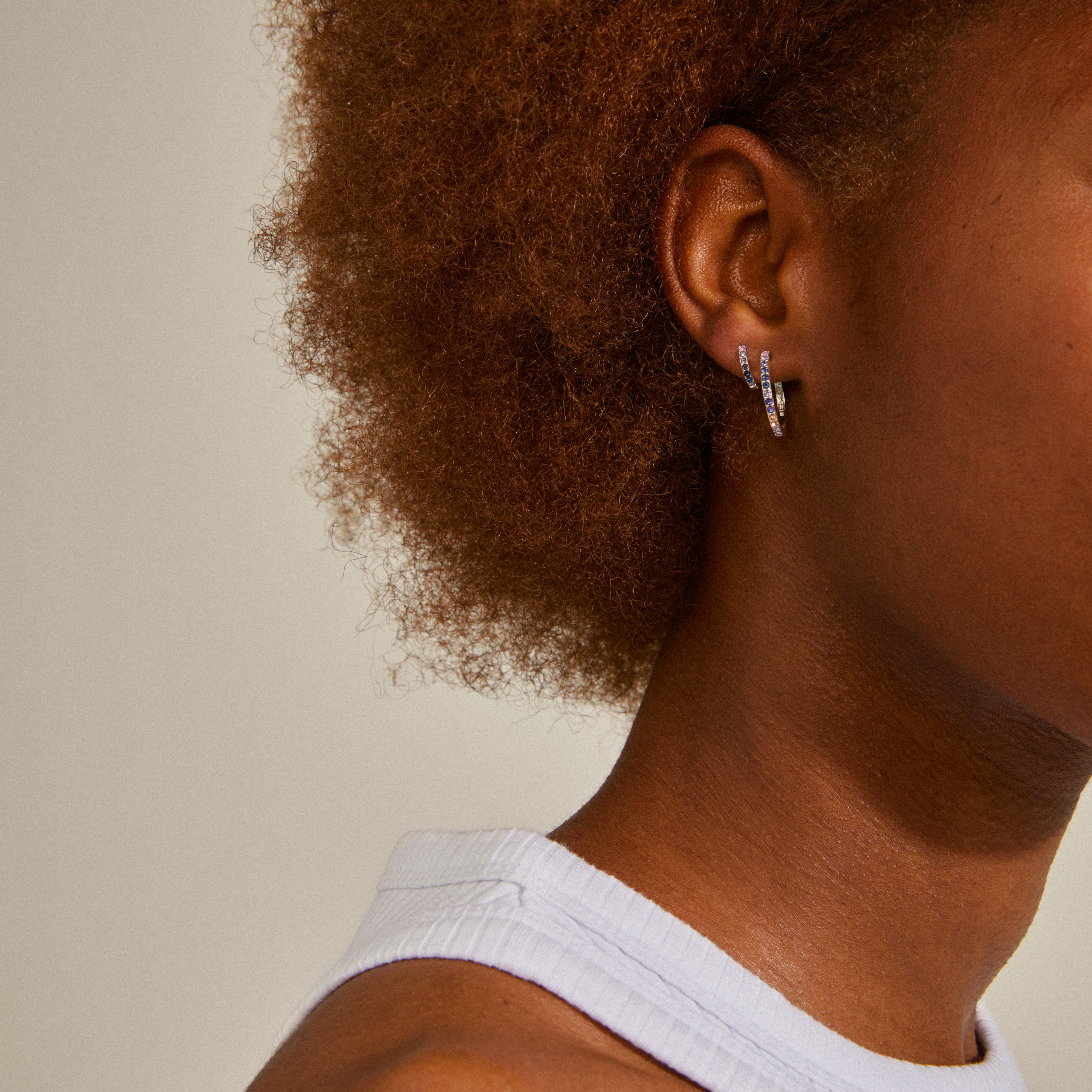 Close-up of a woman's ear adorned with REIGN hoops, a silver-plated, crystal-embellished earring set by Pilgrim, showcasing a stylish blend of elegance and modernity.
