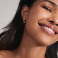 SCOTTIE earrings 2-in-1 set gold-plated, featuring huggie hoops with Preciosa crystals and shiny hoops with detachable crystal pendants, worn by a smiling woman.