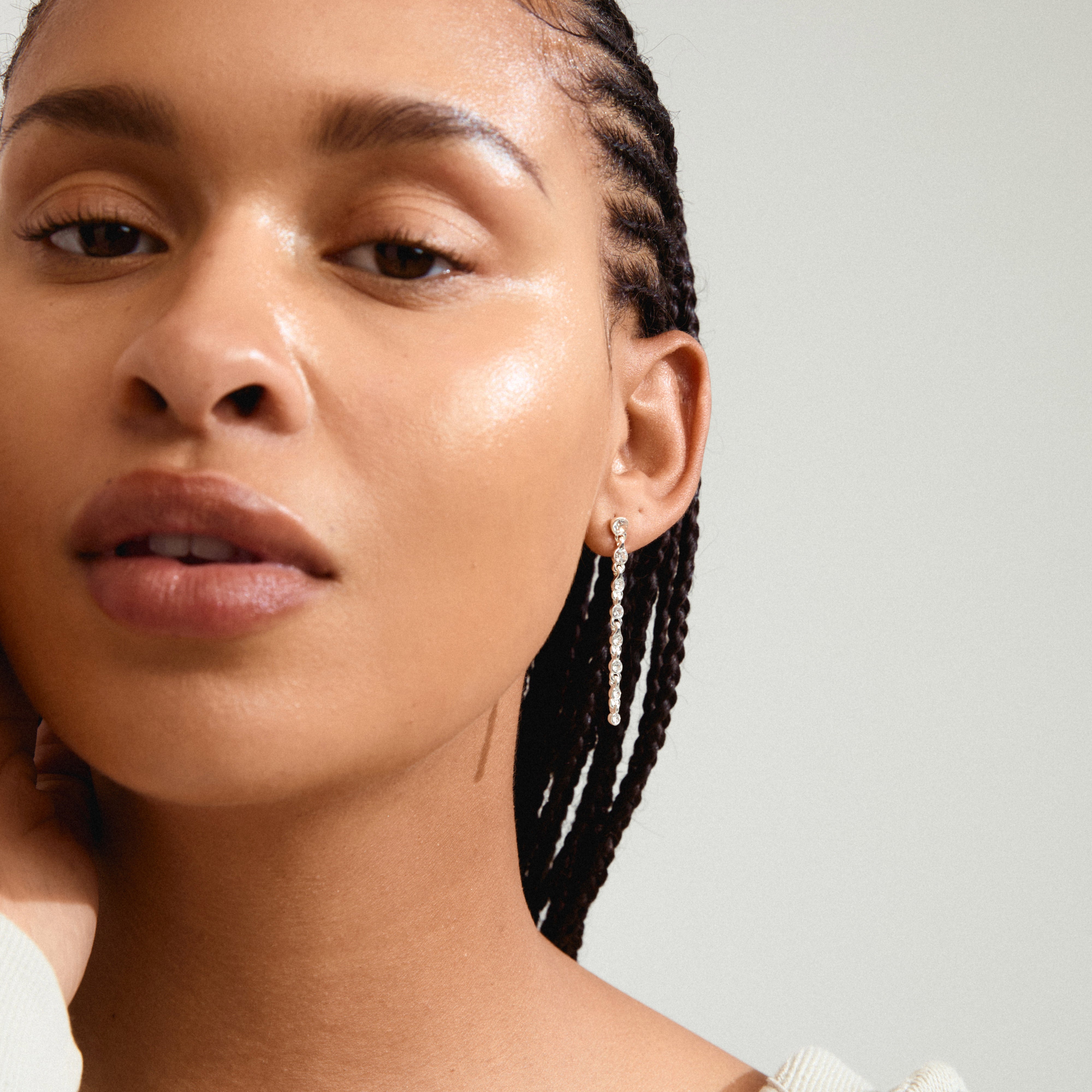 IMOGENE earrings silver-plated, featuring long sparkling Preciosa crystal pendants, showcased by a woman with braids, embodying upscale, conscious fashion.