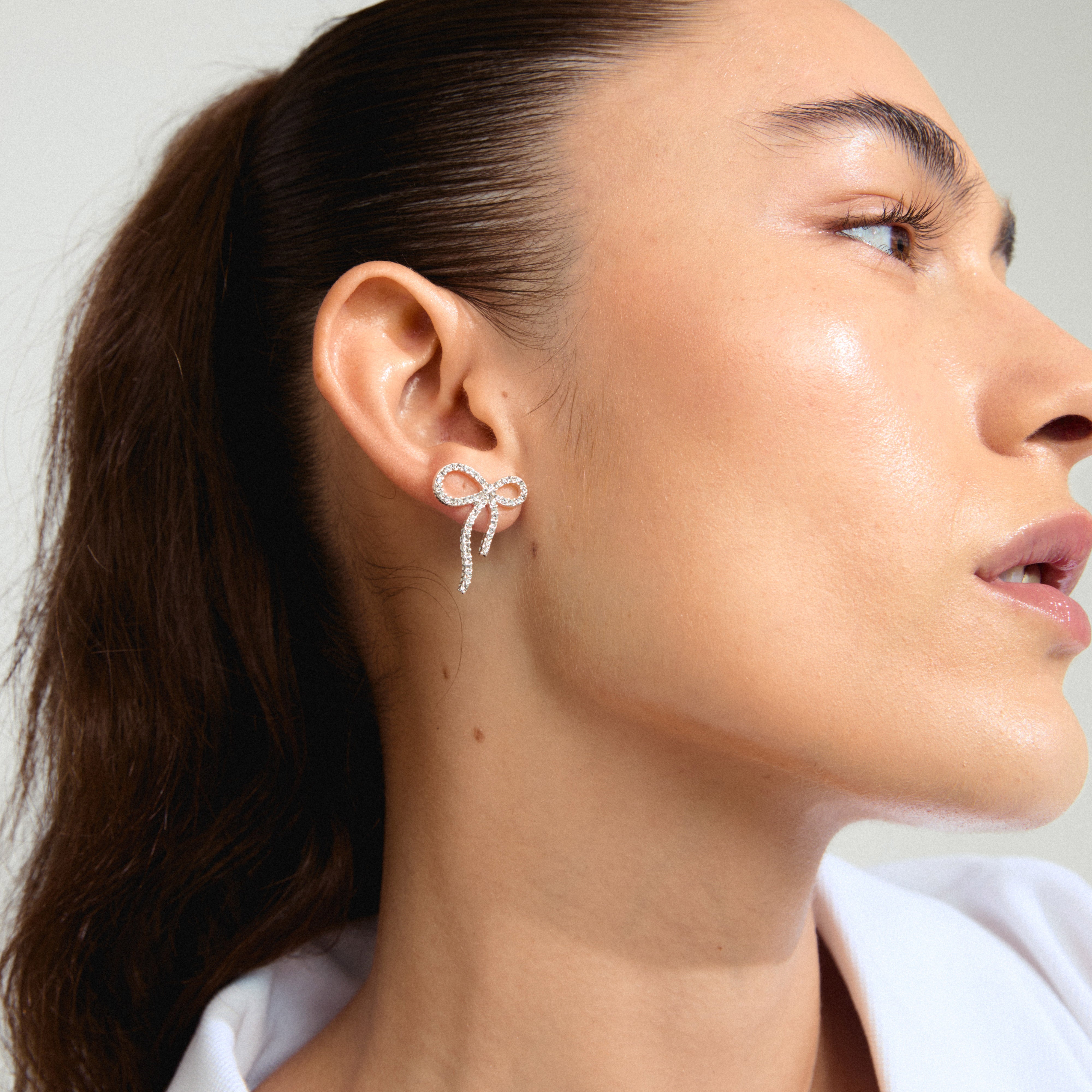 JOLANTA earrings silver-plated: Woman wearing silver-plated bow earrings with Preciosa crystals, showcasing a trendy, elegant look suitable for casual and formal occasions.