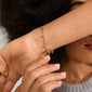 ALAIA gold-plated bracelet with eight tiny heart pendants, offering a romantic and playful look, perfect for daily wear or special occasions.