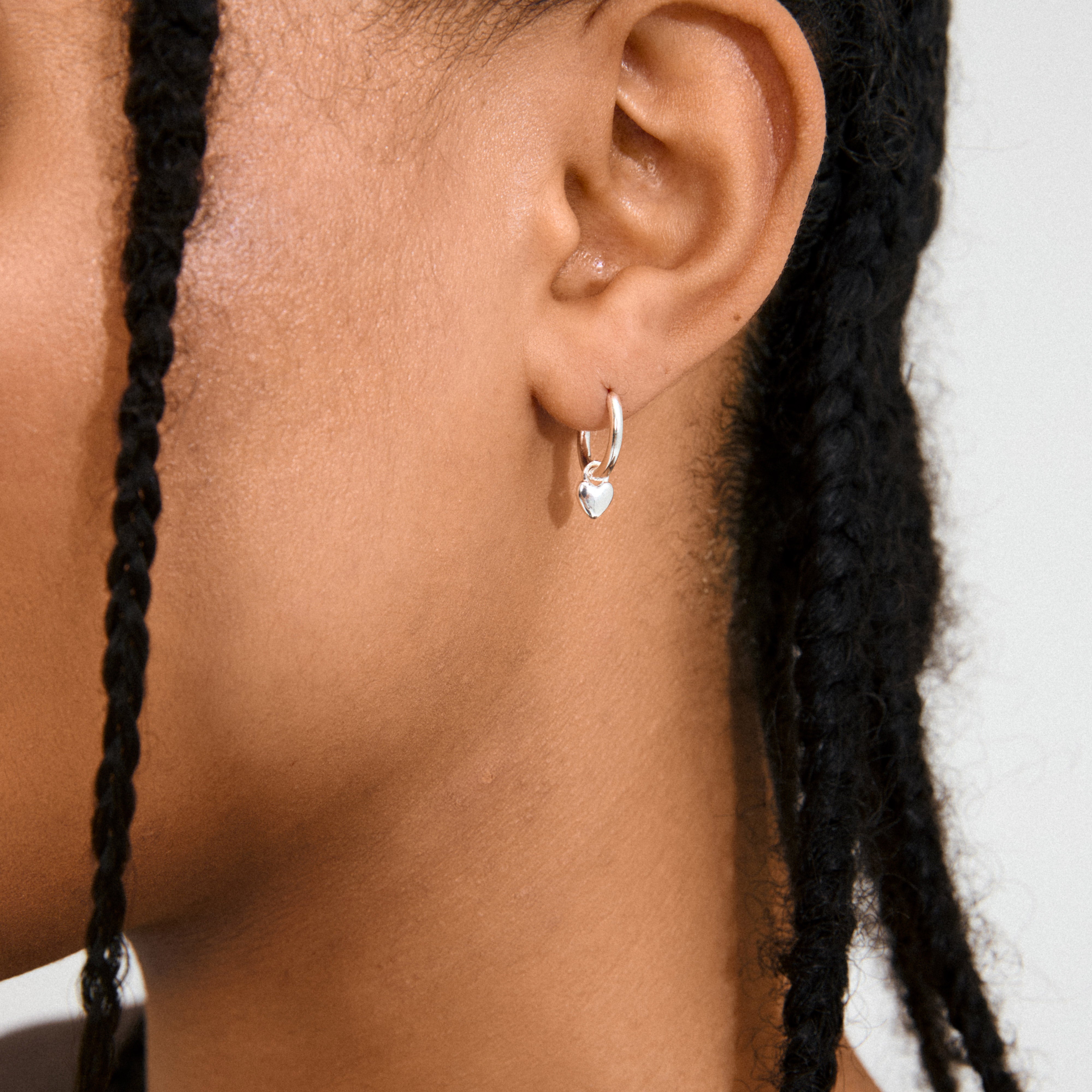 ALAIA earrings silver-plated, featuring versatile huggie hoops with detachable heart pendants, embody a romantic, modern design crafted from 99% recycled material for everyday elegance.