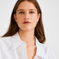 Young woman models ALAIA earrings—silver-plated huggie hoops with detachable petite heart pendant—showcasing their versatility for both daily wear and special occasions.