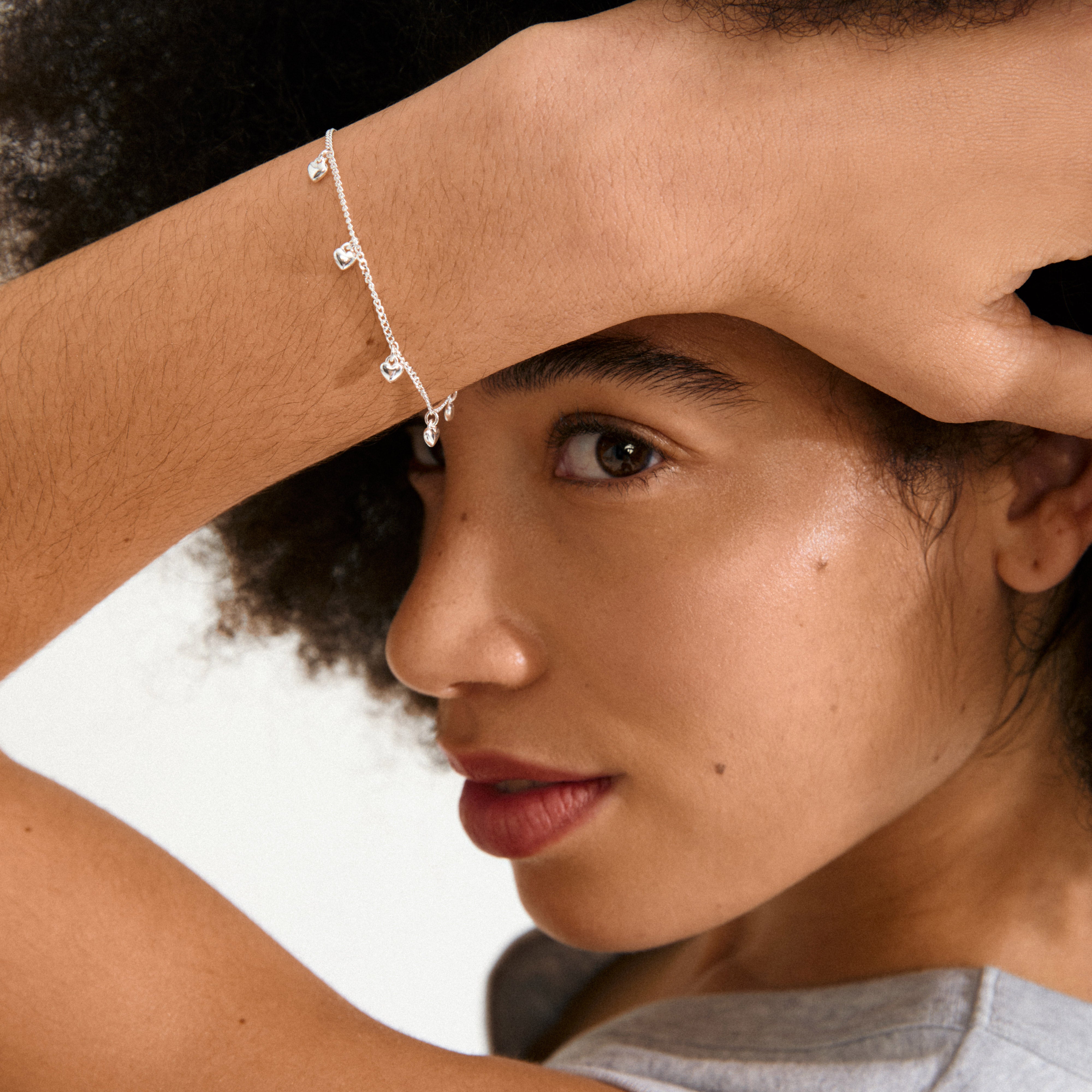 ALAIA bracelet silver-plated, featuring a slim curb chain adorned with eight tiny heart pendants, offering a playful, romantic touch ideal for everyday or special occasions.