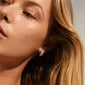 LONA chunky crystal huggie hoops, silver-plated, elegantly adorn a woman's ear, showcasing sparkling Preciosa crystals for an exclusive, classy look.