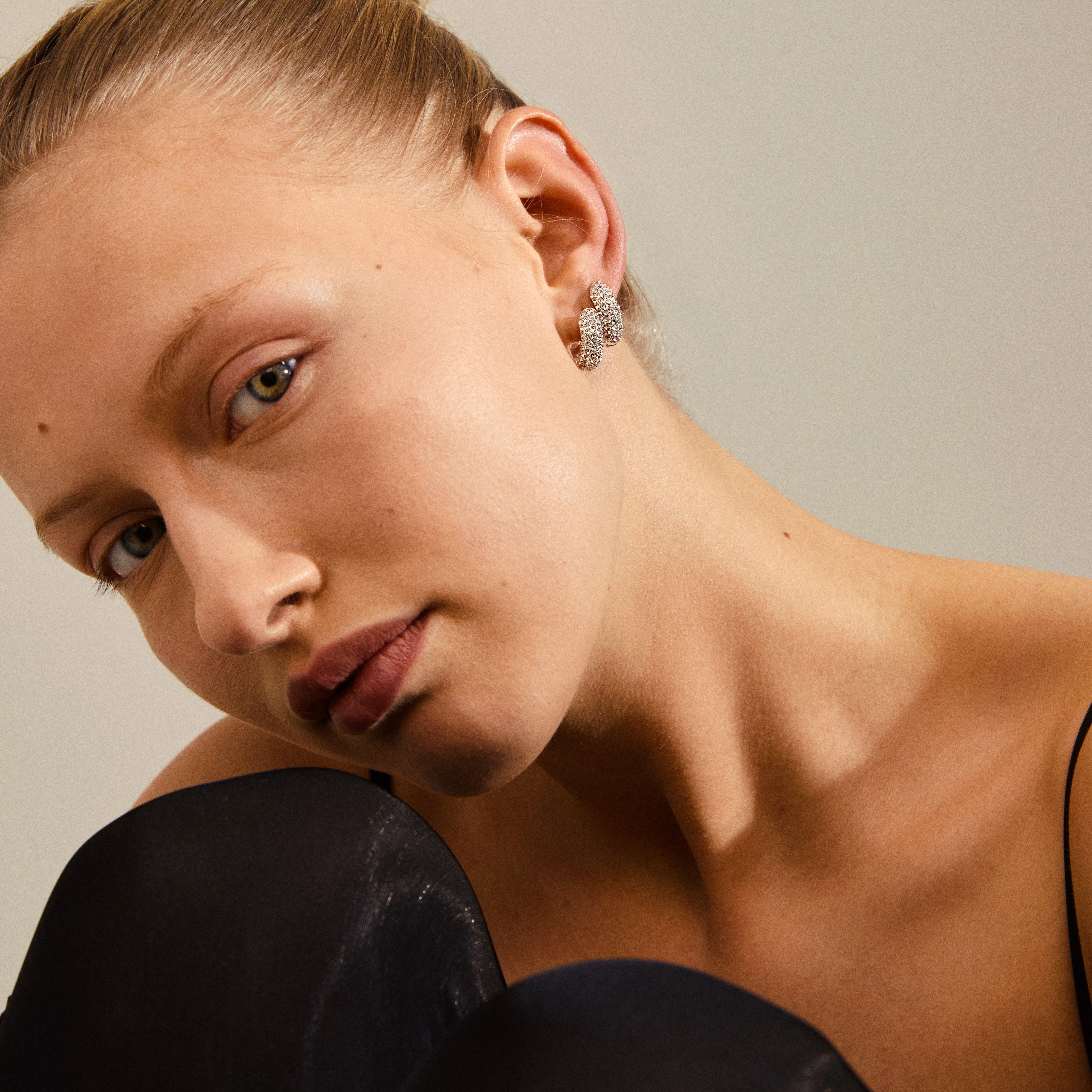 LONA chunky crystal huggie hoops, silver-plated, showcased on a woman, highlighting their recycled material and sparkling Preciosa crystals for an exclusive, sophisticated look.