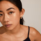 Woman wearing MINE chunky huggie hoops, silver-plated with a shiny, soft design, capturing a classy and feminine look. Perfect for effortless elegance.