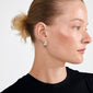 Profile of a person showcasing ALEXANE chunky mini hoop earrings, silver-plated, highlighting their teardrop shape and smooth finish for a retro, minimalist look.