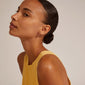 EBNA mini crystal huggie hoops gold-plated worn by woman with a bun, showcasing the gold-plated shine and clear Preciosa crystals.