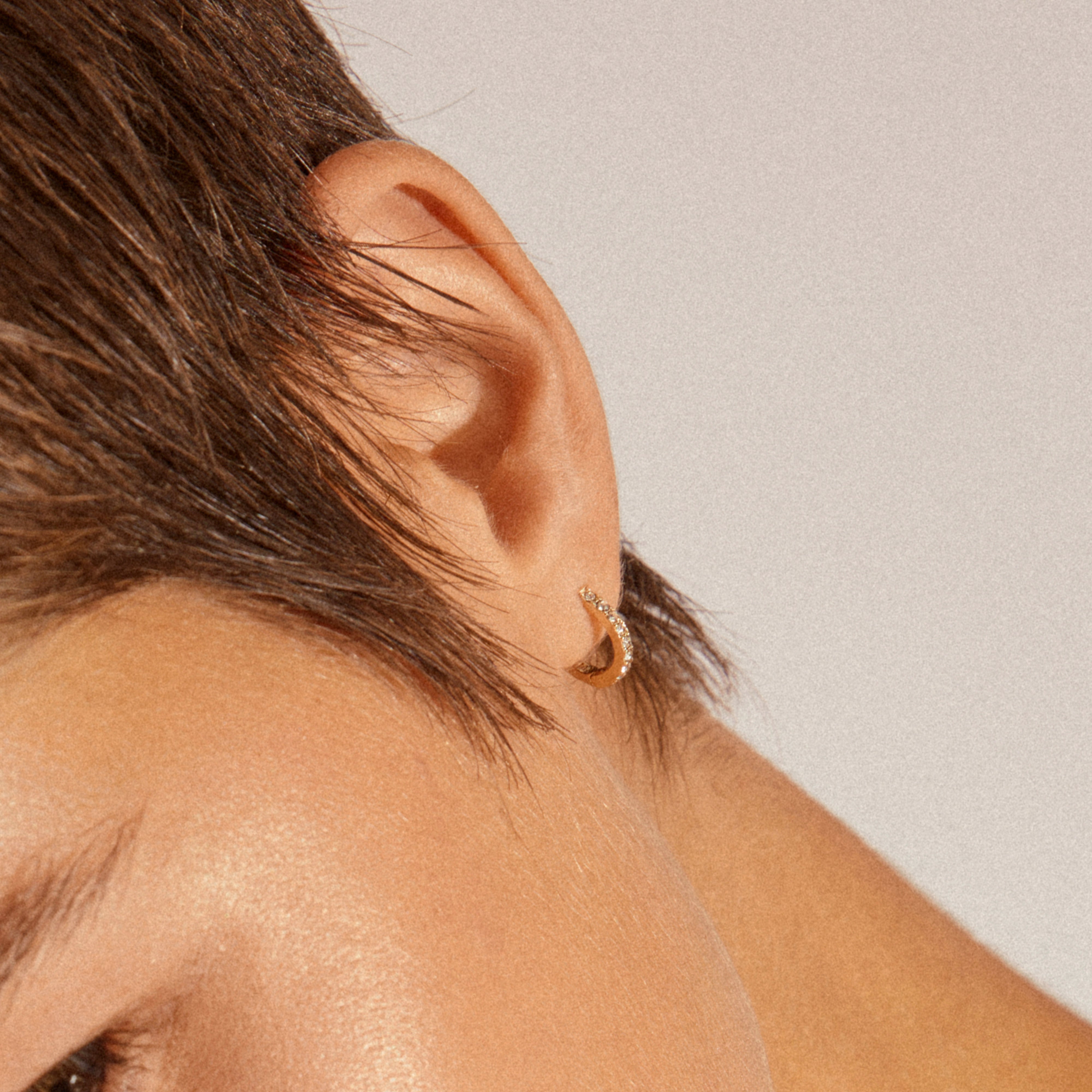 Close-up of an ear wearing EBNA small crystal hoops gold-plated, adorned with sparkling Preciosa crystals, showcasing their elegance and smart click lock design.