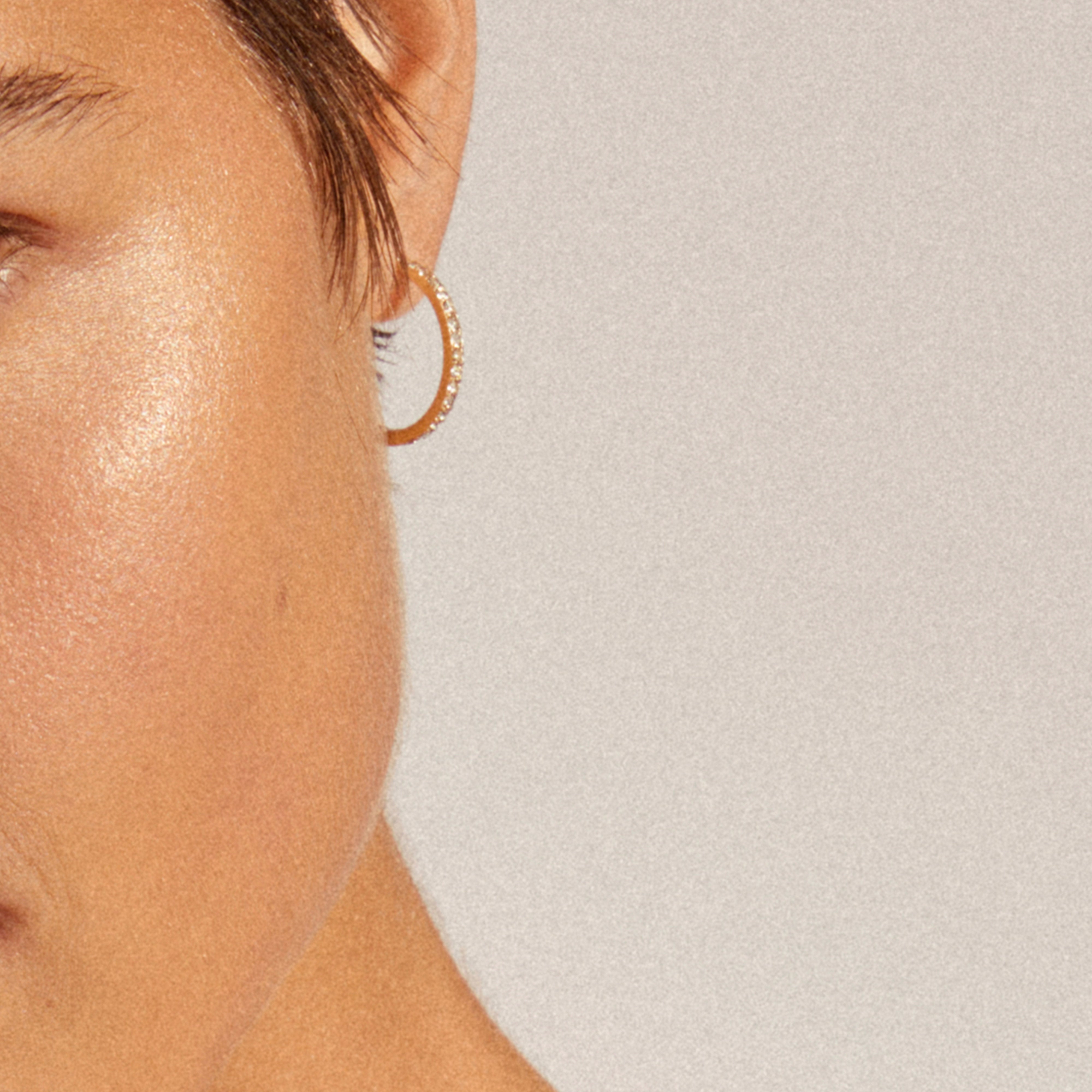 Close-up of a person's face showcasing Pilgrim's EBNA large crystal hoops, gold-plated with shimmering stones, highlighting their elegant and festive appeal.