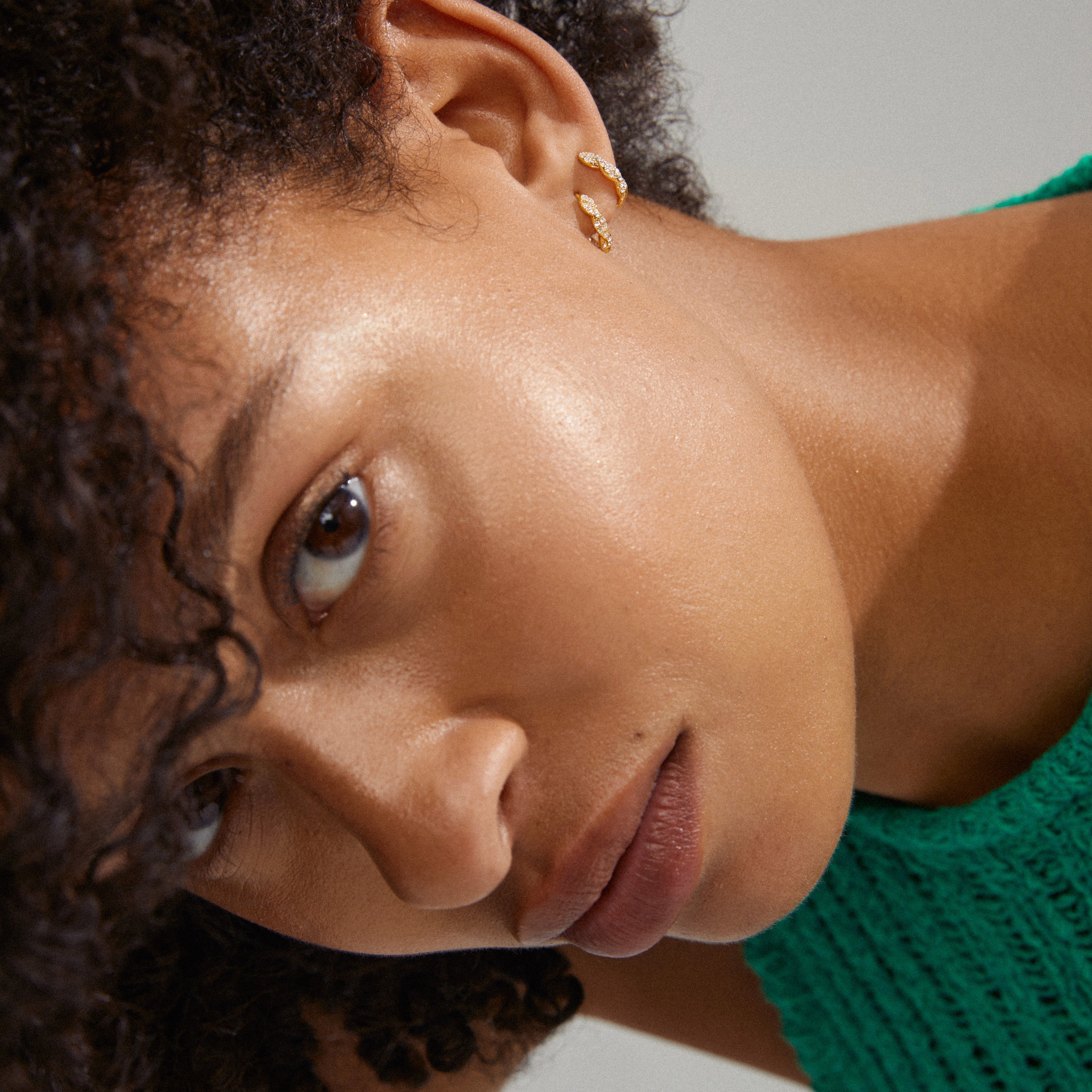 EZO twirled crystal hoops gold-plated, featuring fine twisted details and shimmering Preciosa crystals, elegantly adorn a woman's ear in a close-up view.