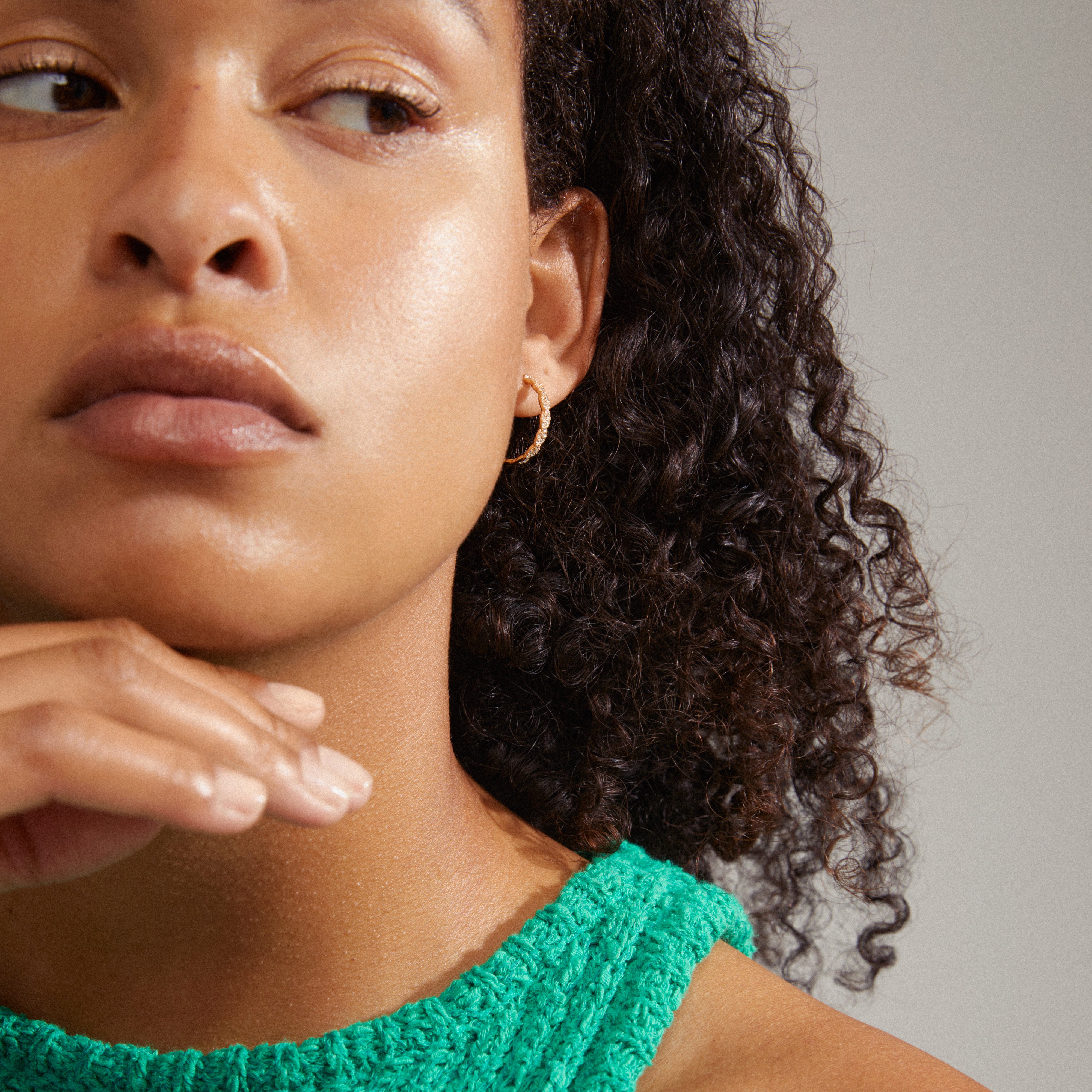 EZO twirled crystal hoops gold-plated, worn by a woman with curly hair, showcase fine twisted details and Preciosa crystals, adding glamour and timeless elegance.
