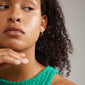 EZO twirled crystal hoops gold-plated, worn by a woman with curly hair, showcase fine twisted details and Preciosa crystals, adding glamour and timeless elegance.