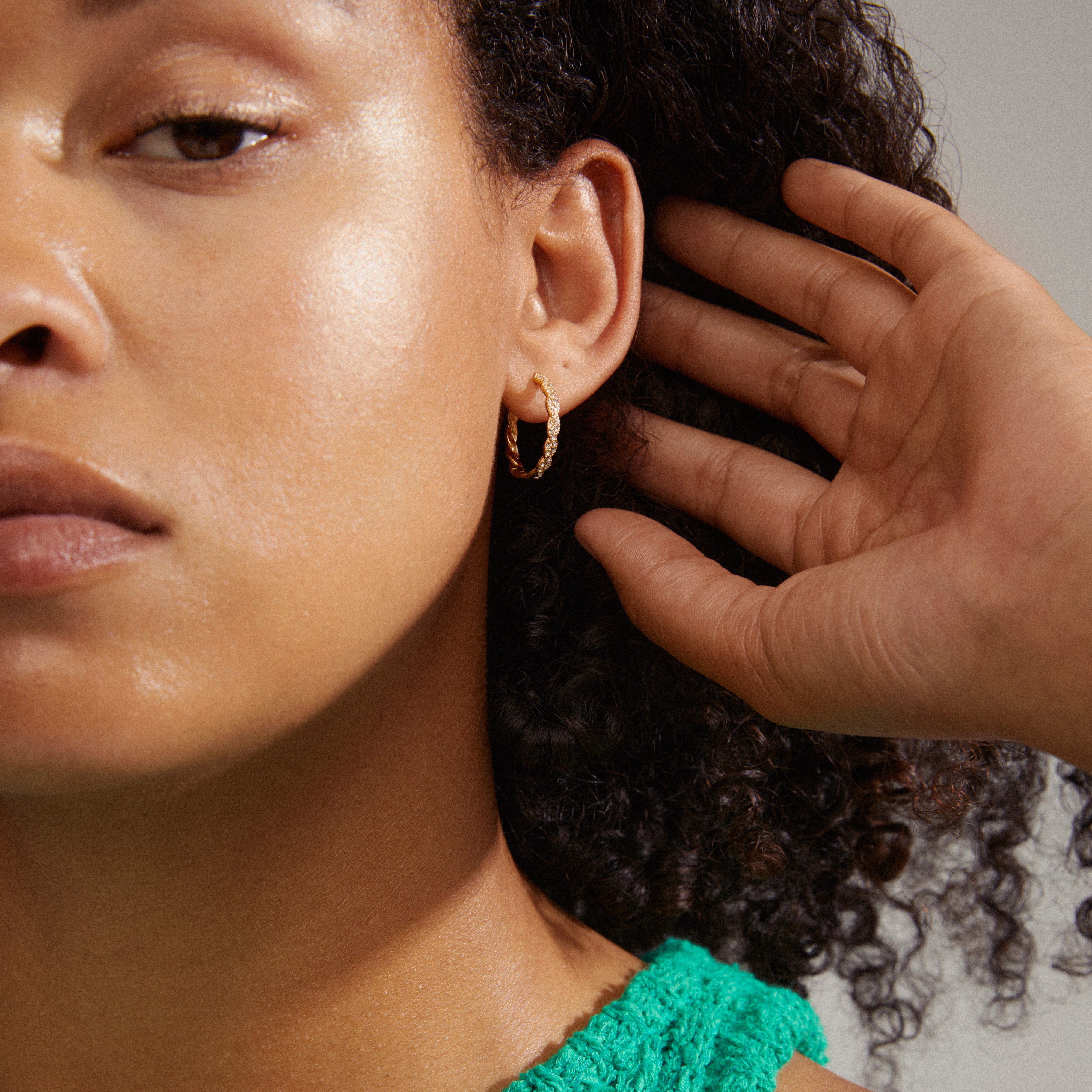 EZO twirled crystal hoops gold-plated adorn a woman's ear, featuring fine twisted details and shimmering Preciosa crystals for a glamorous, timeless style.