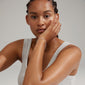 Woman with braids holds her face, showcasing the ROGUE crystal halo bracelet, silver-plated, adorned with sparkling Preciosa crystals from Pilgrim's collection.