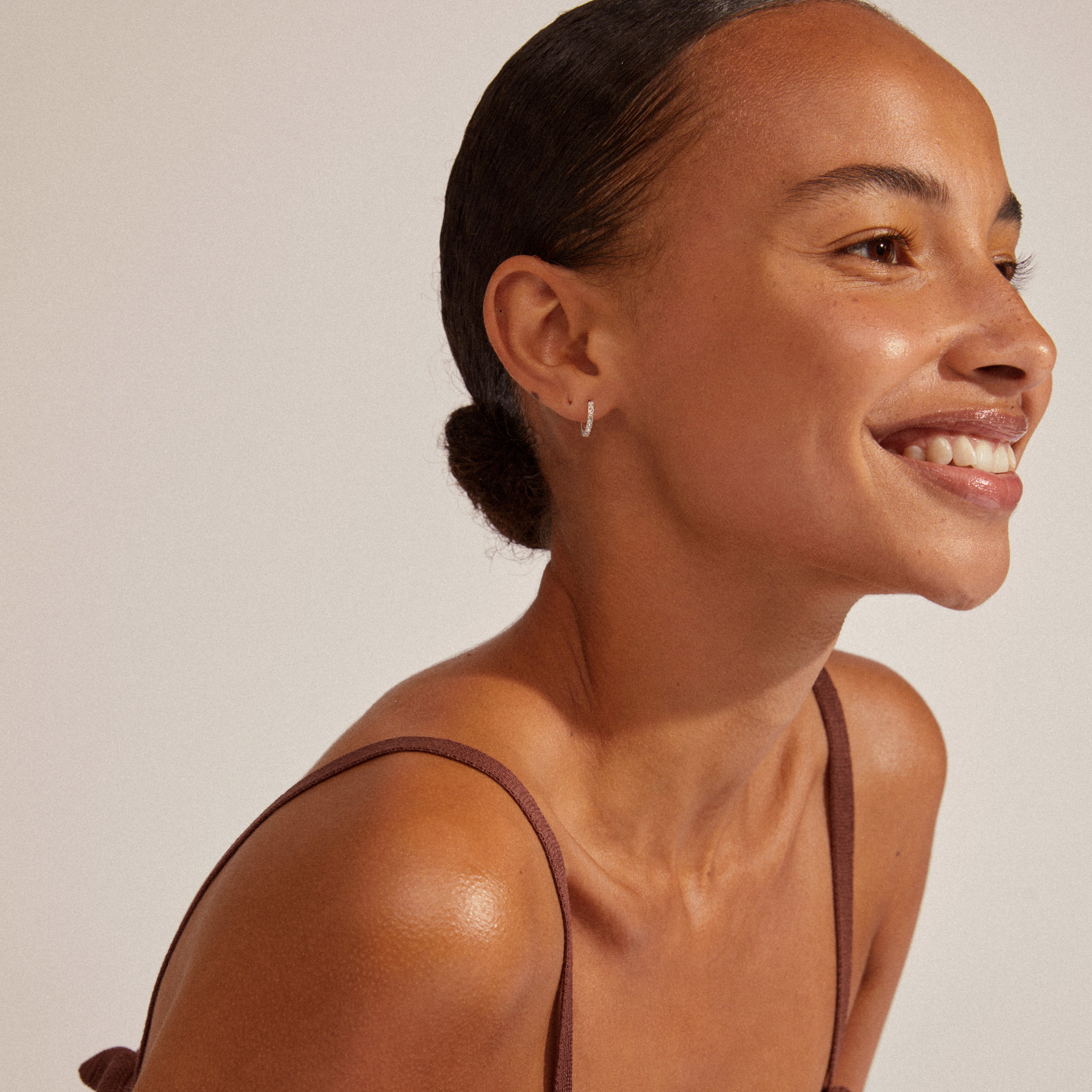 Woman smiling, showcasing EBNA small crystal hoops silver-plated, highlighting their elegance and ease of use with a smart click lock for stylish, minimalist accessorizing.