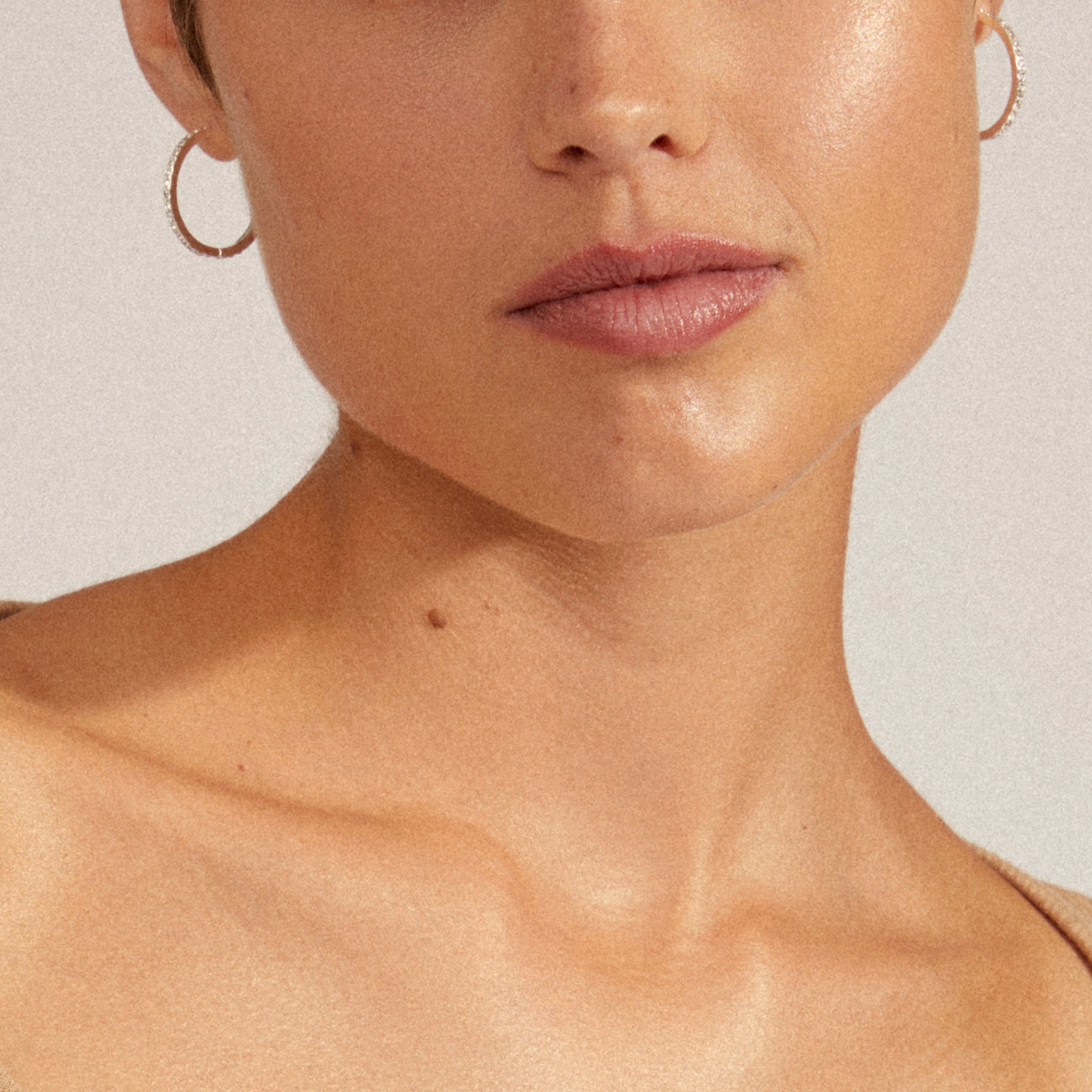 Close-up of a person wearing EBNA maxi crystal hoops, silver-plated earrings by Pilgrim, showcasing their smooth design and easy-to-use click lock.