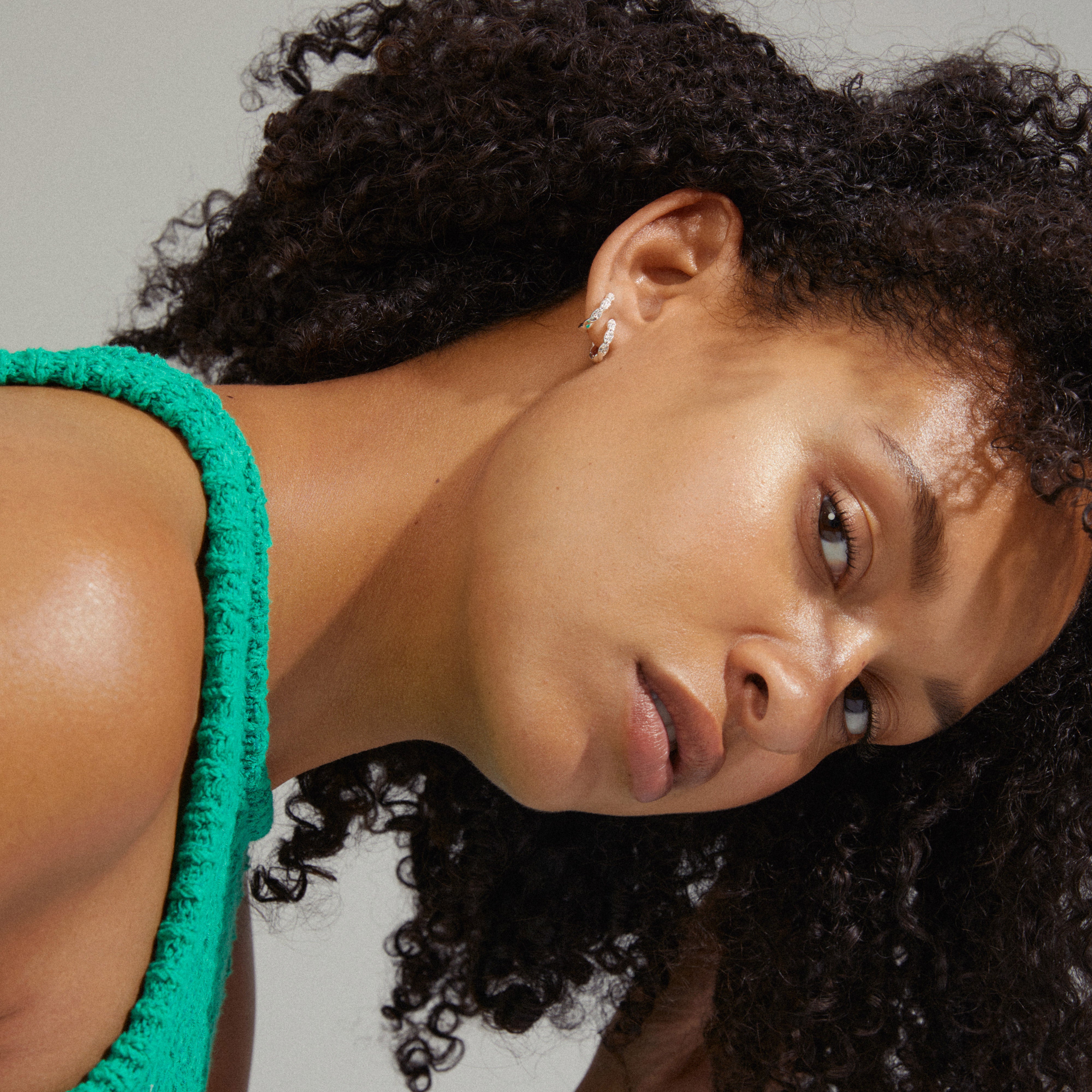 Woman wearing EZO twirled crystal hoops, silver-plated with twisted details and Preciosa crystals, highlighting elegant shine and timeless style.