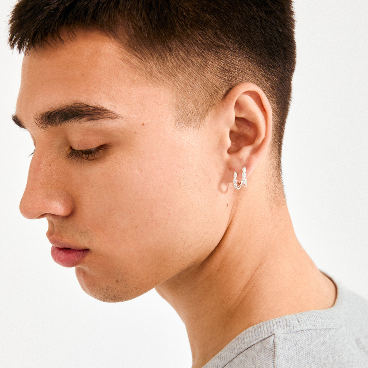 Young person wearing EZO twirled crystal hoops silver-plated, featuring sculptural twists and sparkling crystals, capturing a blend of elegance and bold style.