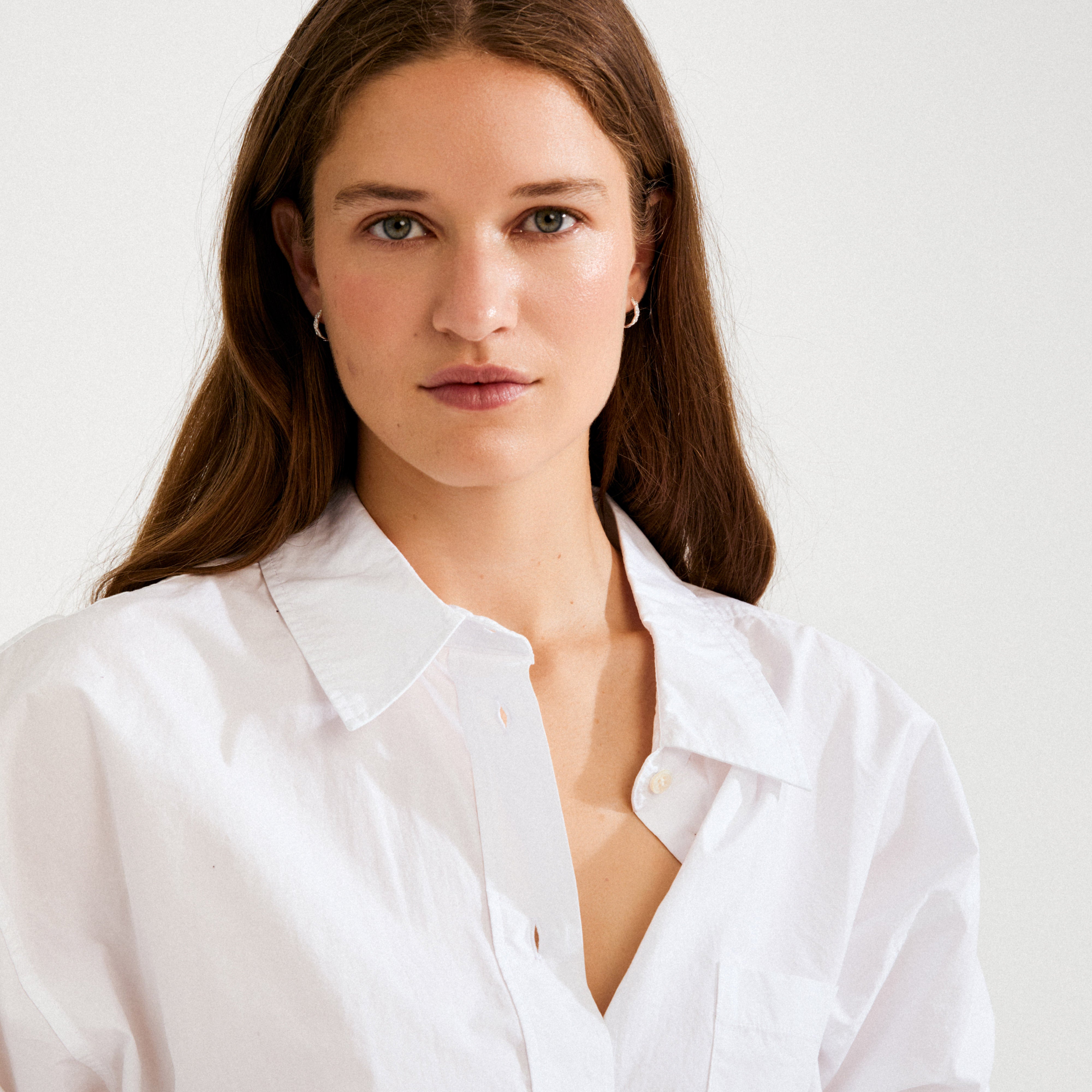 Young woman models EZO twirled crystal hoops, silver-plated, showcasing their elegant twisted design and shimmering Preciosa crystals.