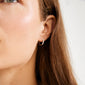 Close-up of a person wearing EZO twirled crystal hoops silver-plated, showcasing sculptural twists and sparkling stones. Ideal for elevating any look with elegance.