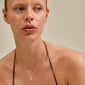 REMY necklace gold-plated featuring a small half moon pendant on a woman, highlighting its dreamy, unique design with an uneven surface and adjustable length.