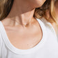 WRENLEY necklace gold-plated, featuring a slim chain with a crystal-adorned pendant, elegantly draped on a woman's neck.