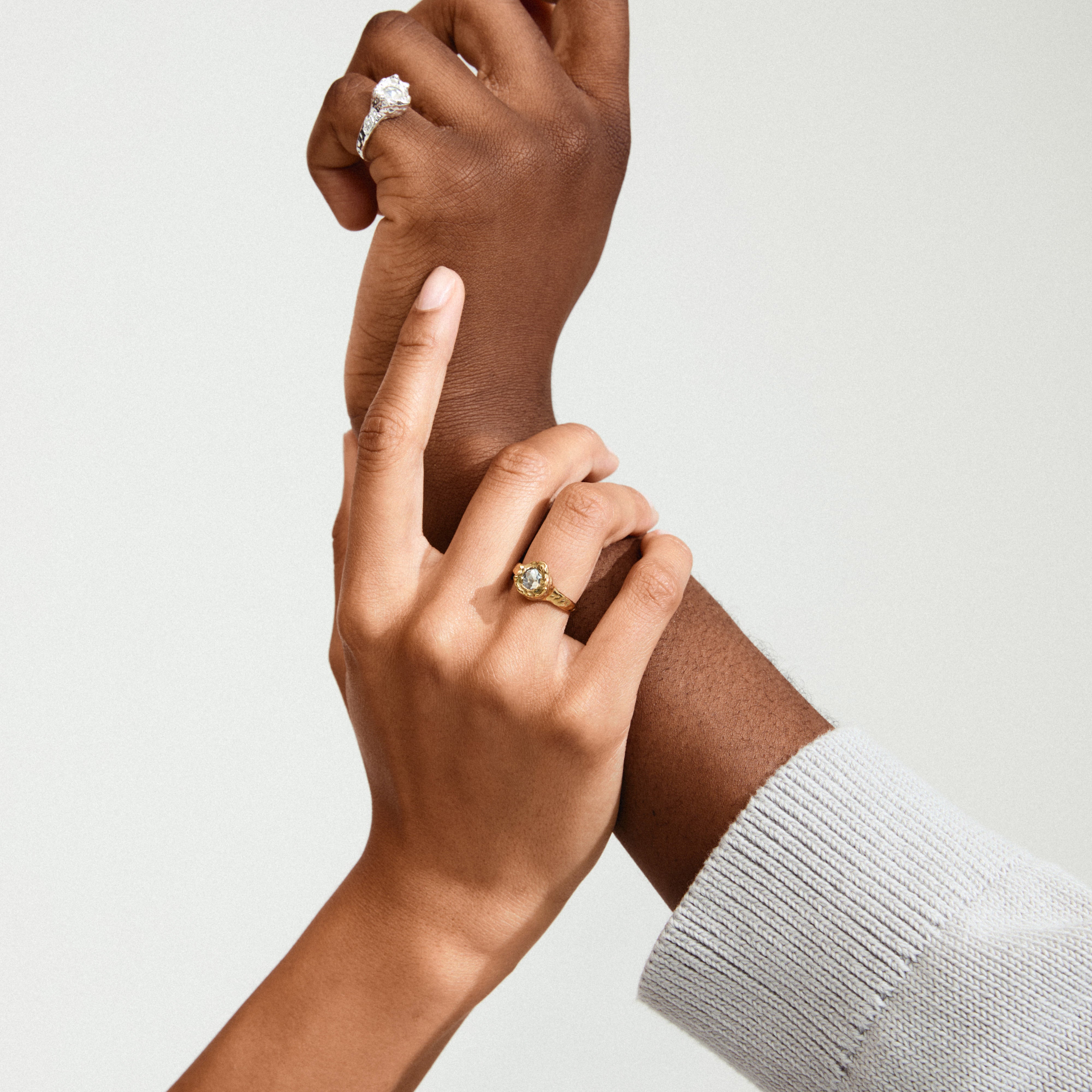 Hands clasped, showcasing the CALLUM ring gold-plated from Pilgrim, featuring a large Preciosa crystal in an organic bezel, adding sparkle and personality.