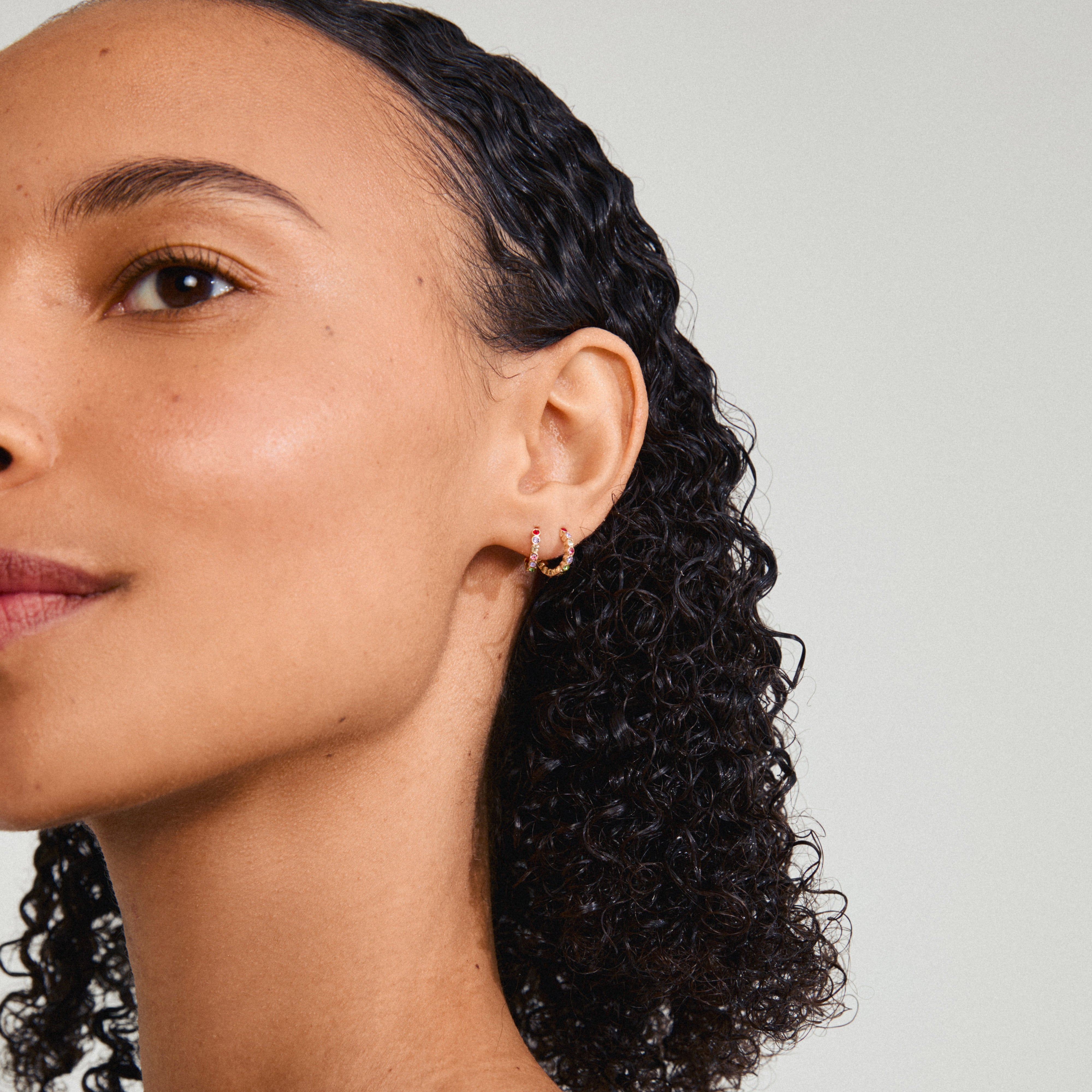 KLEOPRATRA earrings gold-plated, featuring colorful Preciosa crystals, worn by a woman with curly hair. Perfect for adding sparkle and style effortlessly.
