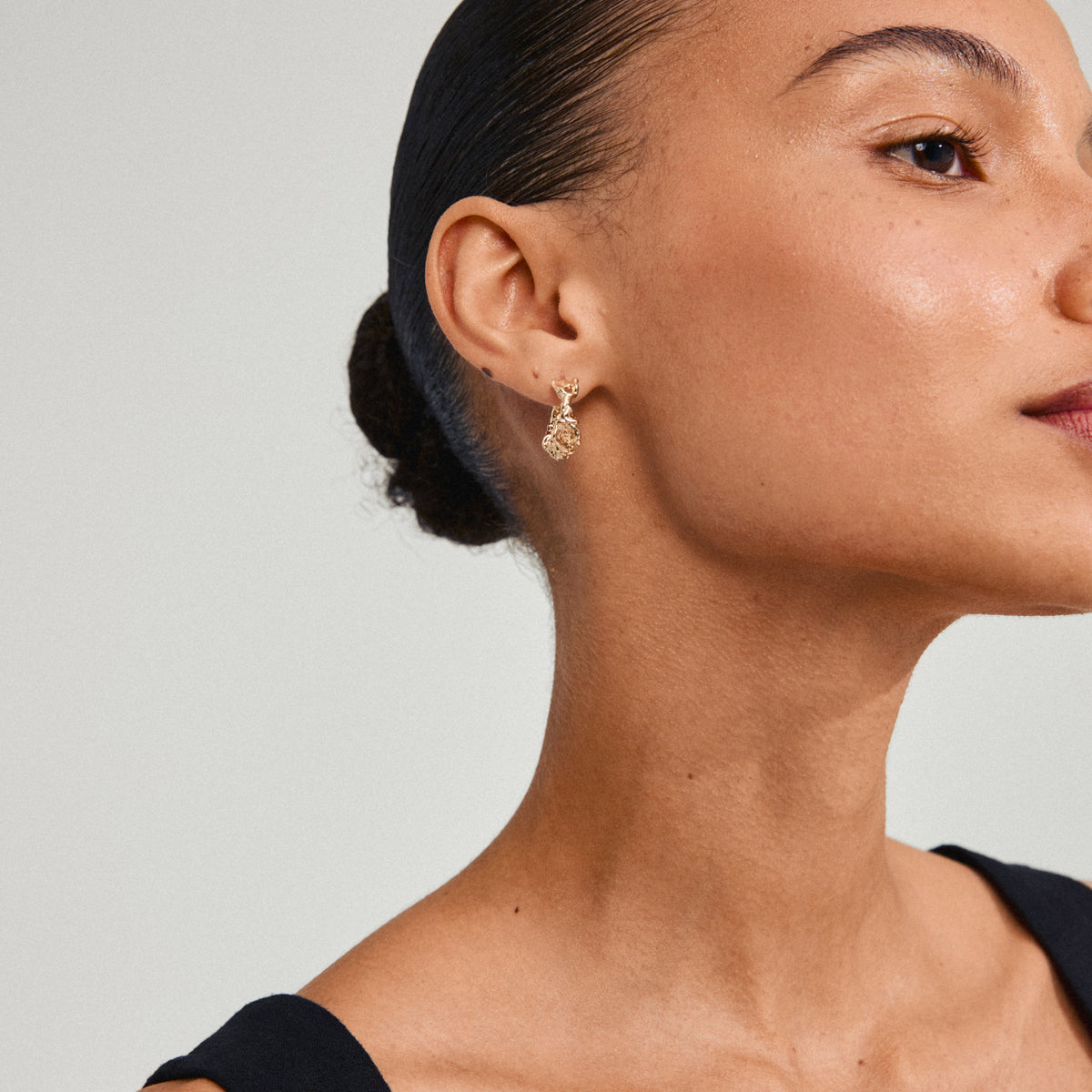 Close-up of a woman's ear wearing Pilgrim's TRUST gold-plated hoop earring, showcasing its elegant, organic design.