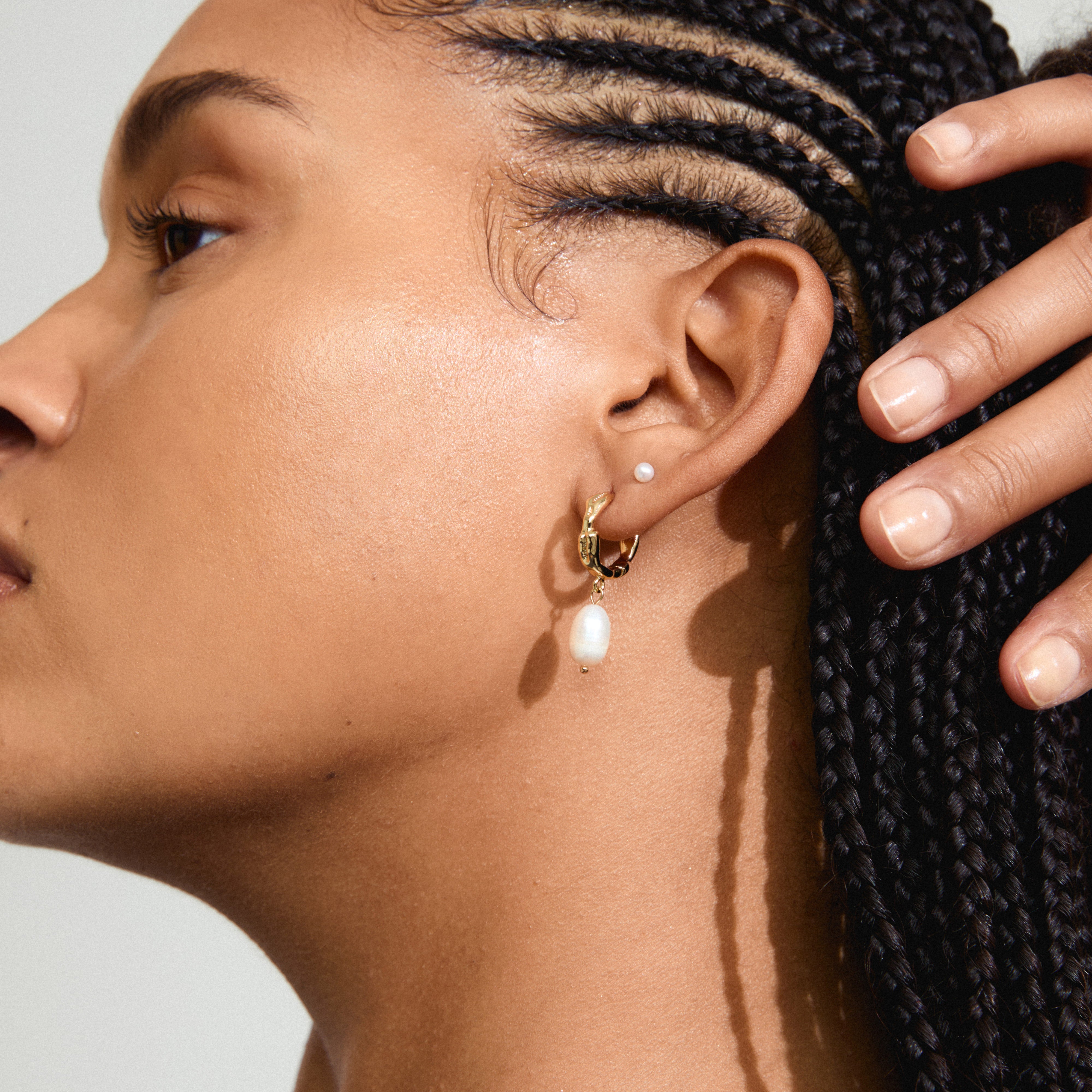 JONNE pearl earrings, 2-in-1 set, gold-plated, featuring organic hoops and freshwater pearl pendants, worn by a woman with braided hair.