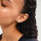 Woman with curly hair wearing LYSANDRA silver-plated bow earrings, highlighting their trendy, recycled design as a stylish everyday accessory.
