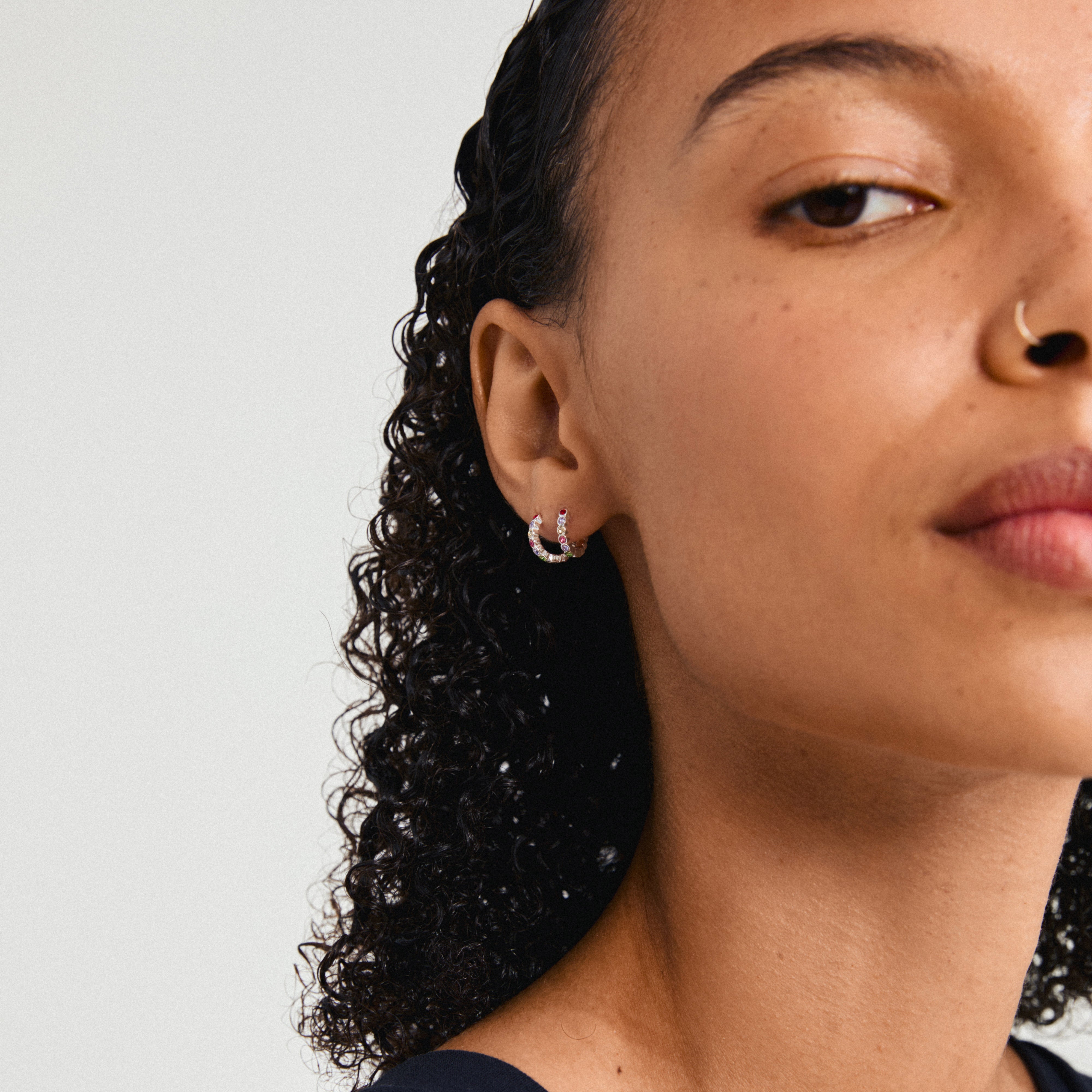 KLEOPRATRA earrings silver-plated, featuring multicolored Preciosa crystals, shown worn by a woman with curly hair and a nose ring.