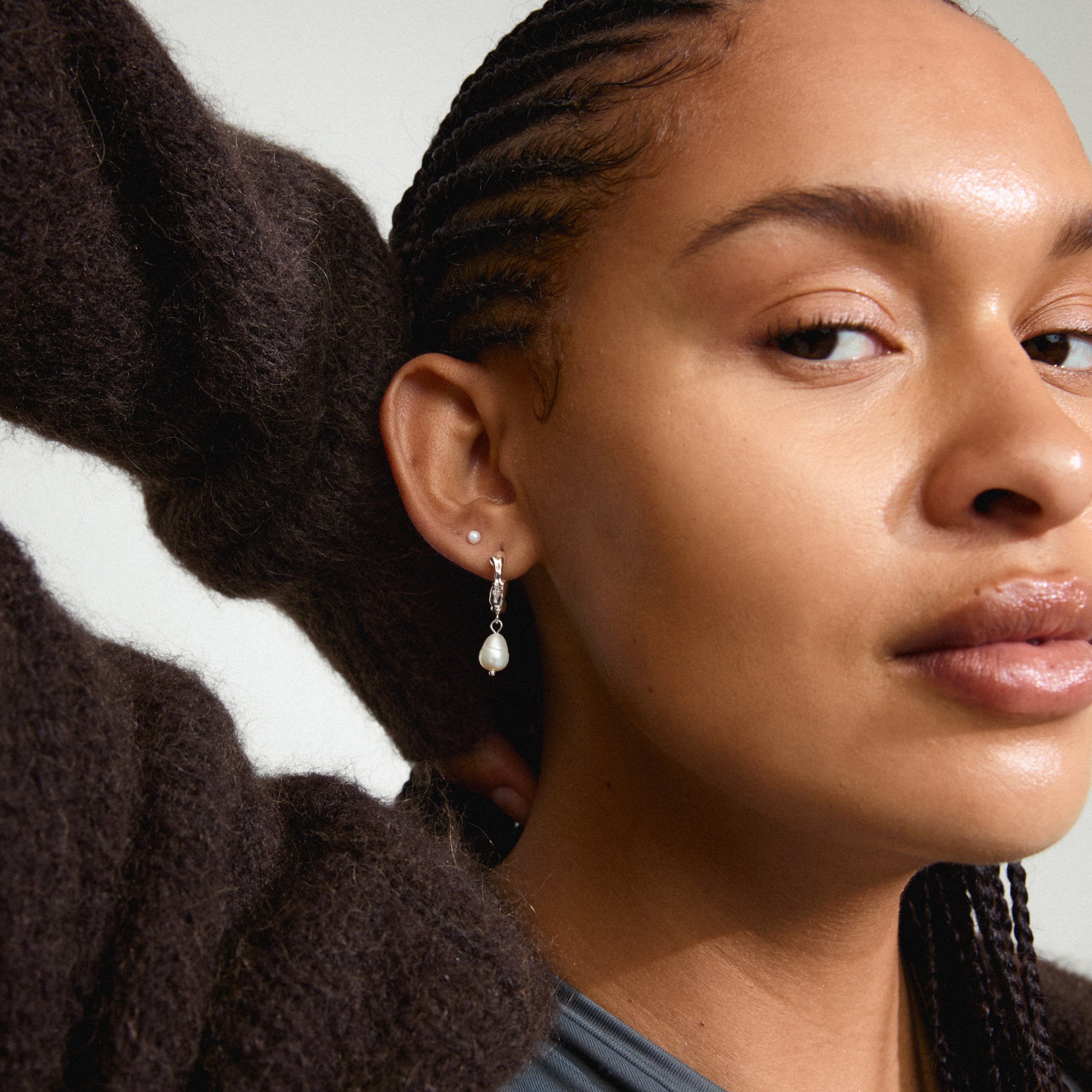 Close-up of a woman wearing JONNE pearl earrings, 2-in-1 set, silver-plated, showcasing the freshwater pearl pendant and classic pearl stud.