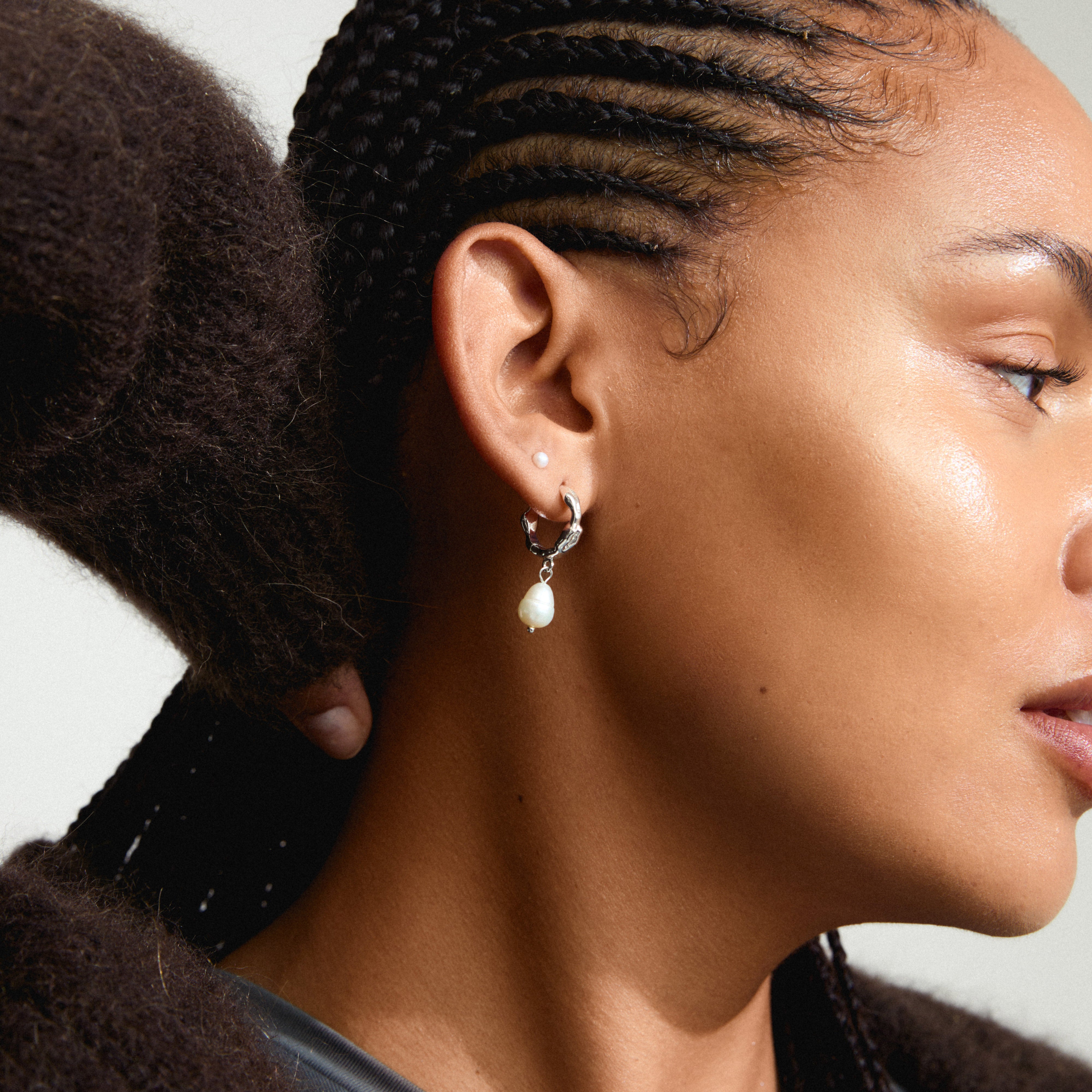 JONNE pearl earrings, 2-in-1 set, silver-plated, featuring freshwater pearls on hoops and classic studs, worn by a woman with braided hair.