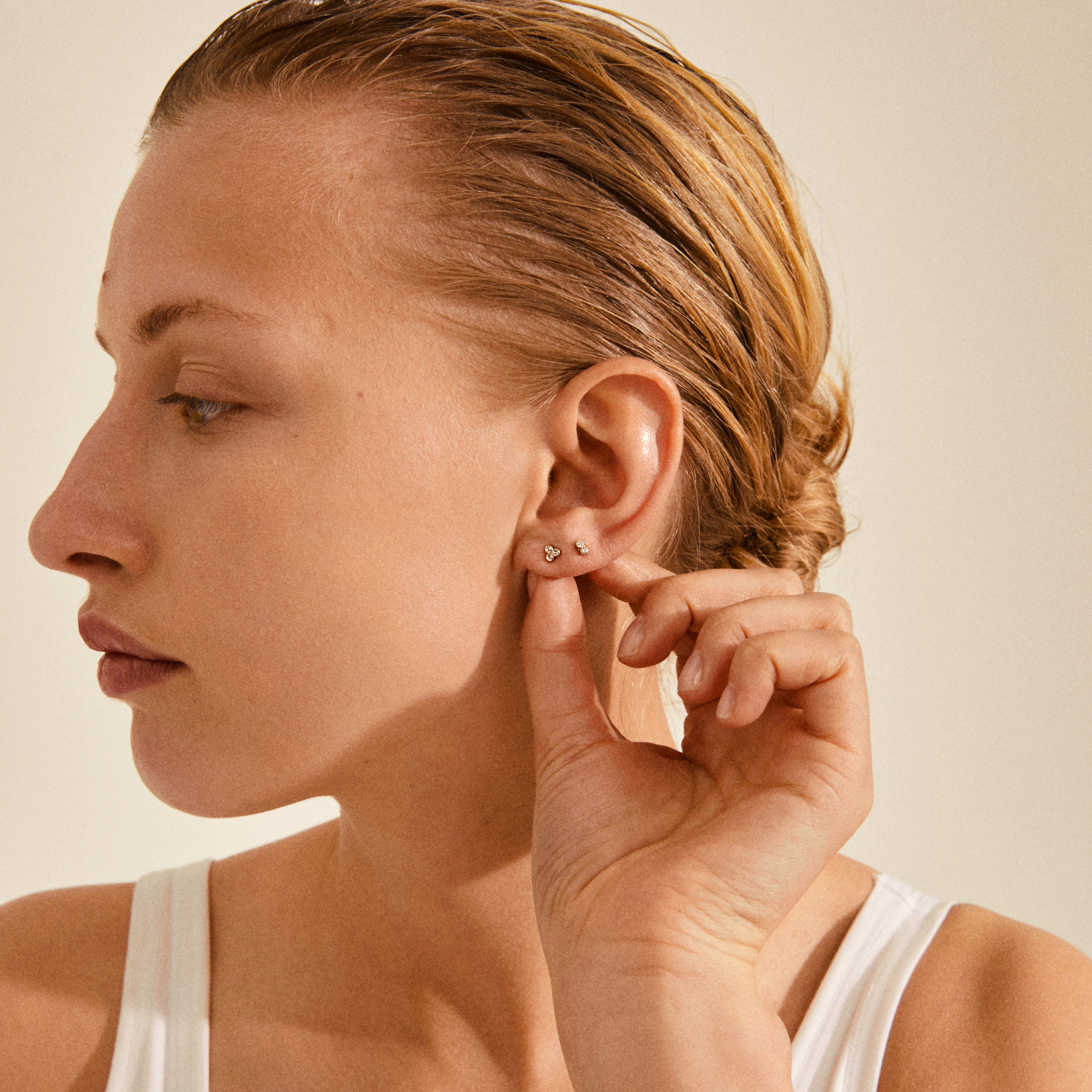 Woman wearing white tank top showcasing KAMARI crystal stud earrings set, gold-plated, emphasizing elegant design with Preciosa crystals, ideal for sharing and celebrating friendships.